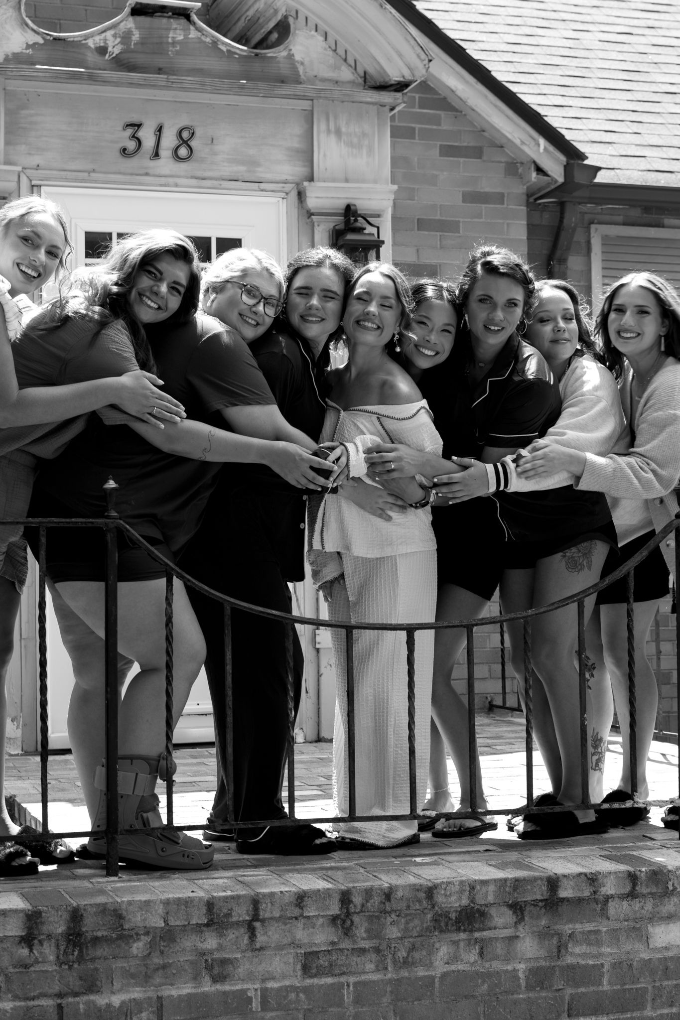 A diverse group of women joyfully standing together on a porch, showcasing friendship in front of a charming house