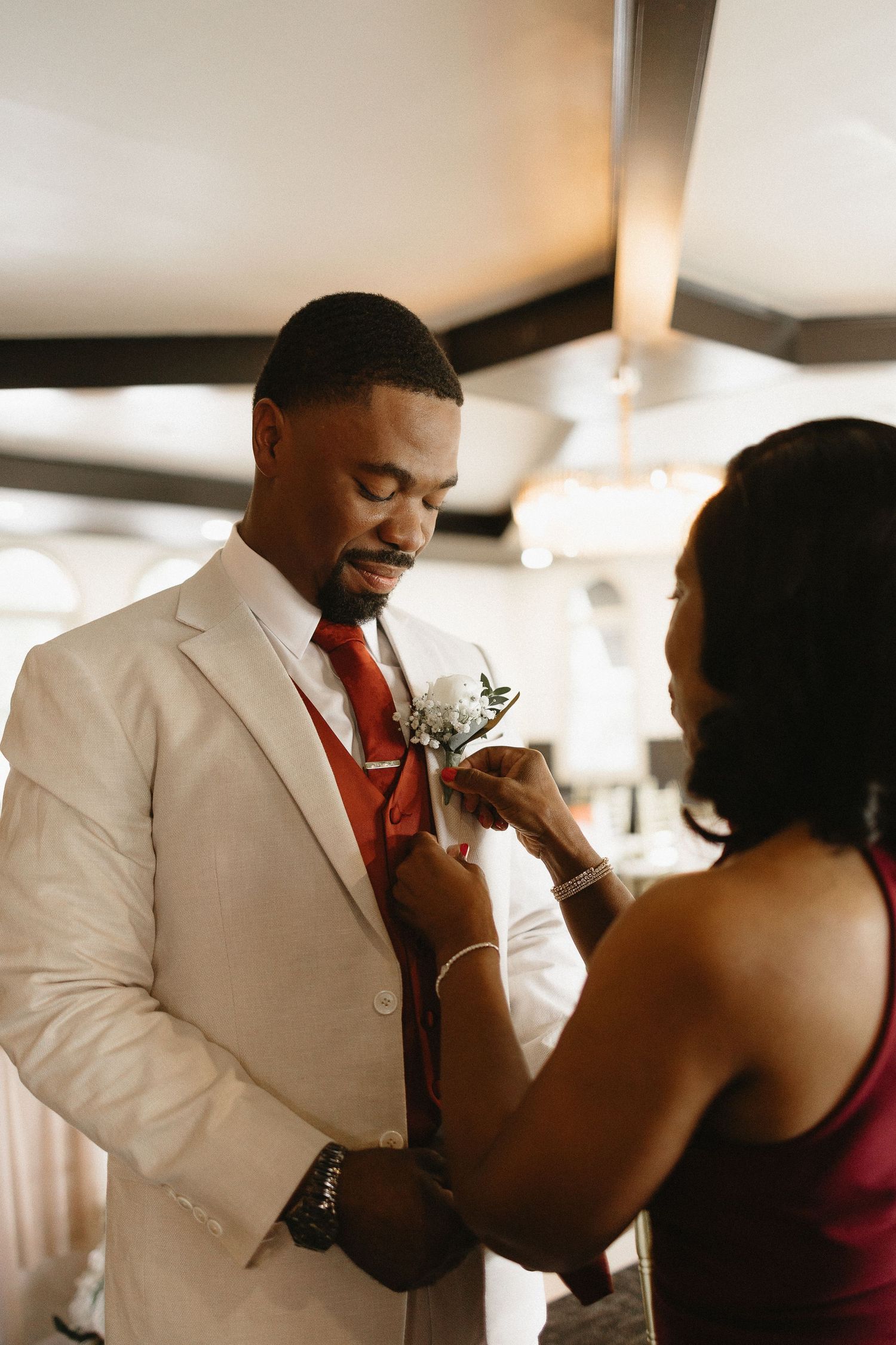 Wedding attendants help pin boutonniere flowers during pre-ceremony preparations.