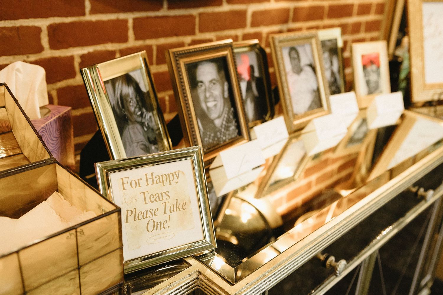 Row of framed photographs displayed on a brick wall.