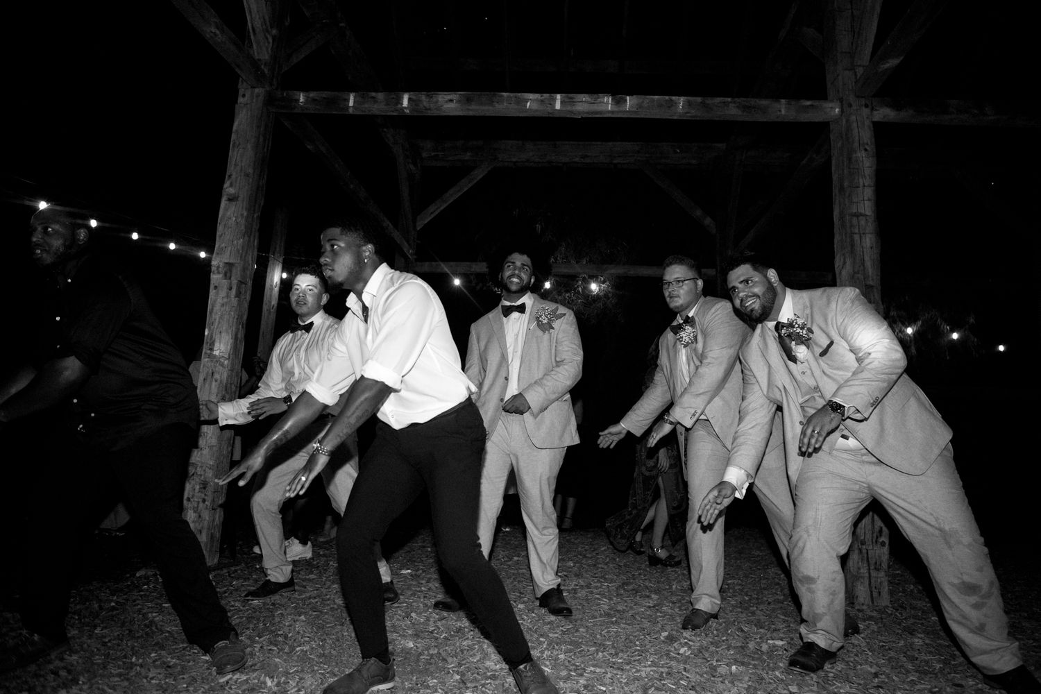 People dancing in a line at an outdoor party captured in black and white photography.