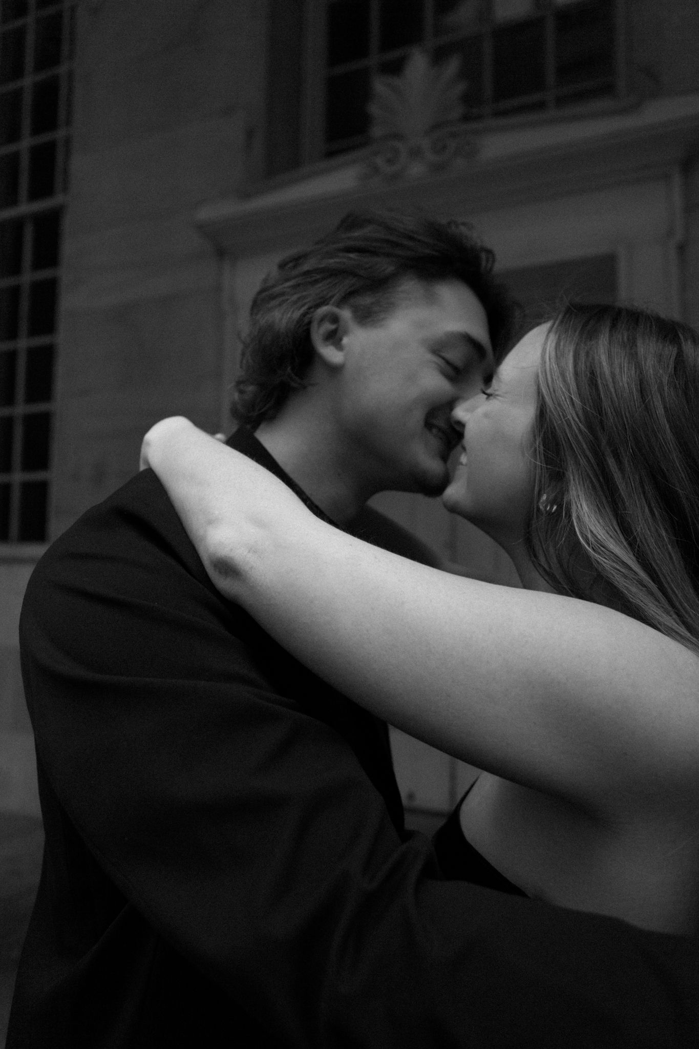 Black and white photo of an engaged couple embracing and smiling, sharing an intimate moment in downtown Louisville