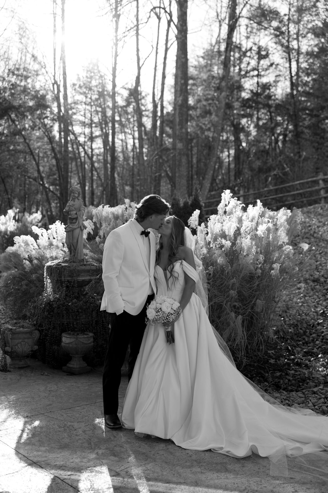 Black and white wedding portraits captured in a scenic outdoor garden setting.