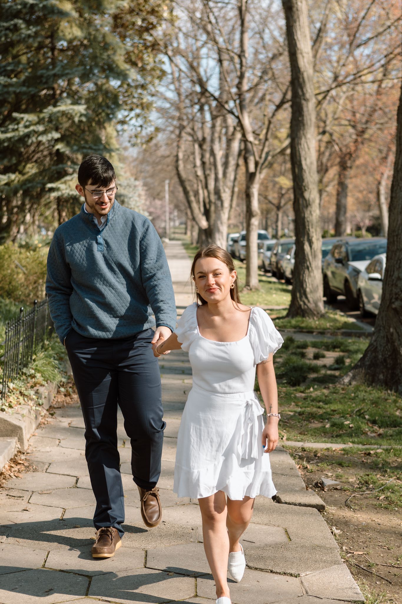 Engaged couple walking hand in hand down a historic street in Old Louisville on a crisp, cold day