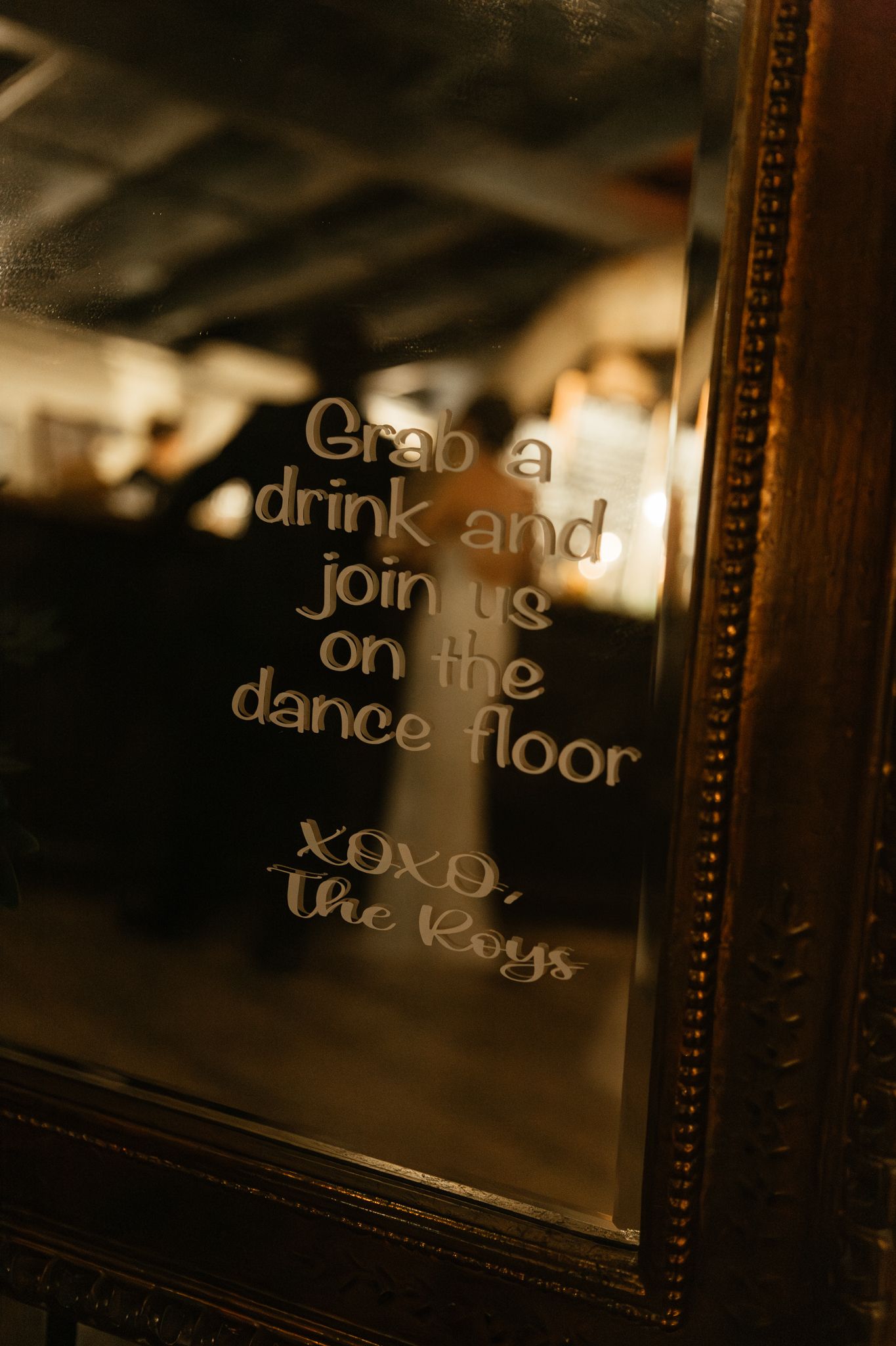 A mirrored sign with gold lettering inviting guests to grab a drink and join the dance floor.