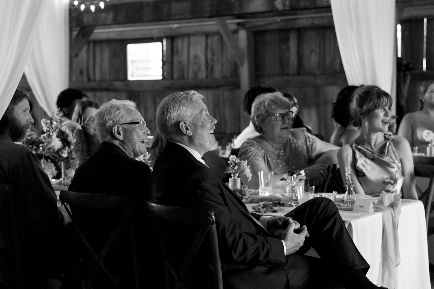 Wedding presents are stacked on tables as guests mingle during an elegant black and white reception ceremony.