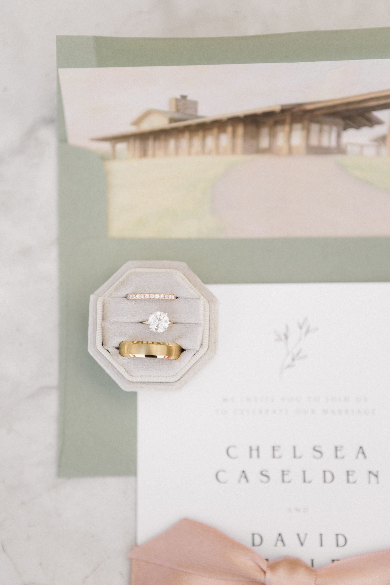 Wedding invitation suite features elegant white stationery with names and ring box details in a soft, romantic style.
