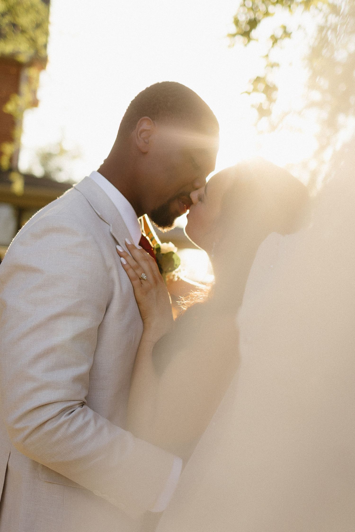 Golden hour portrait of groom in cream suit with sunlight creating a warm glow.