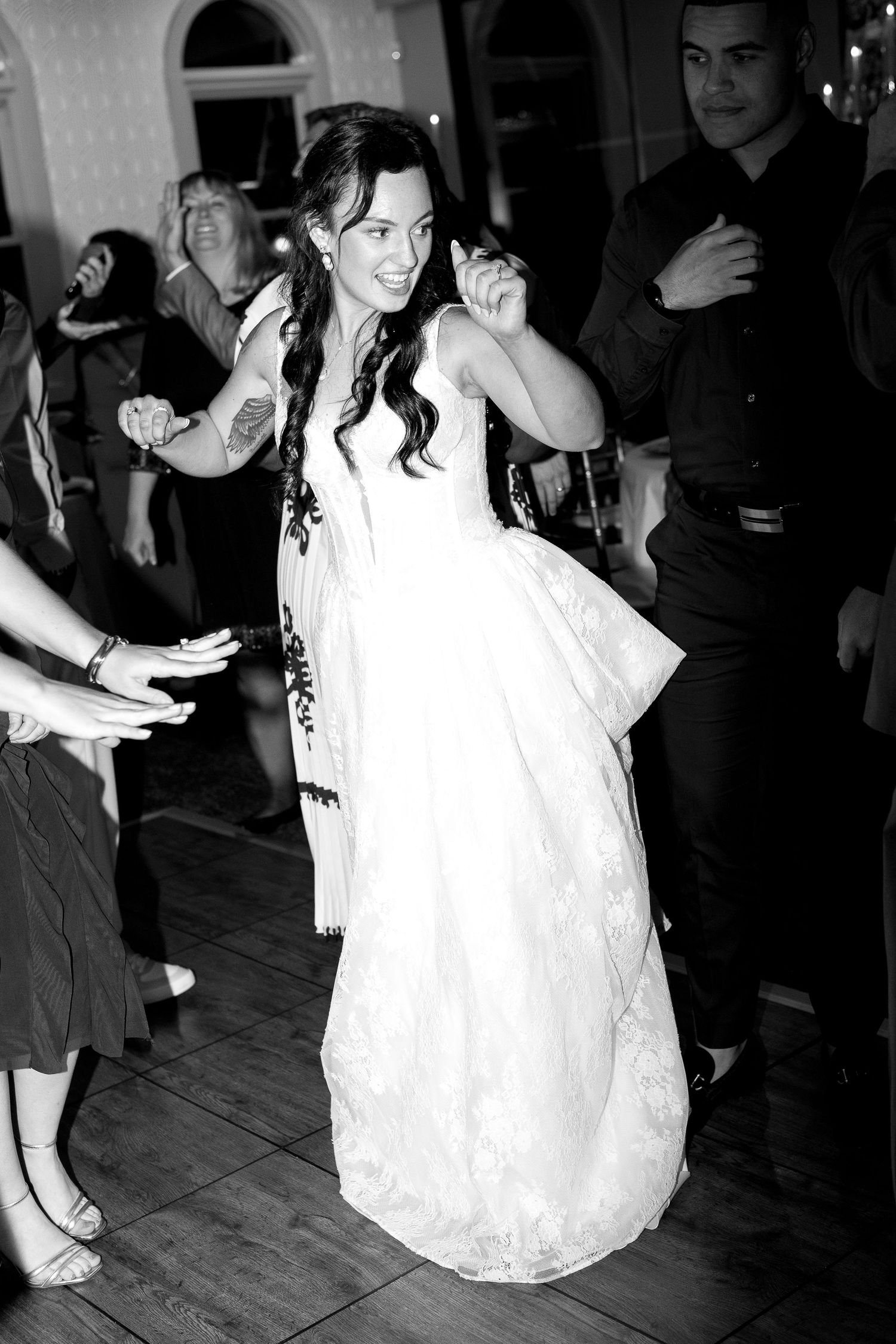 Wedding reception dance floor scene with flowing white dress in black and white photography.