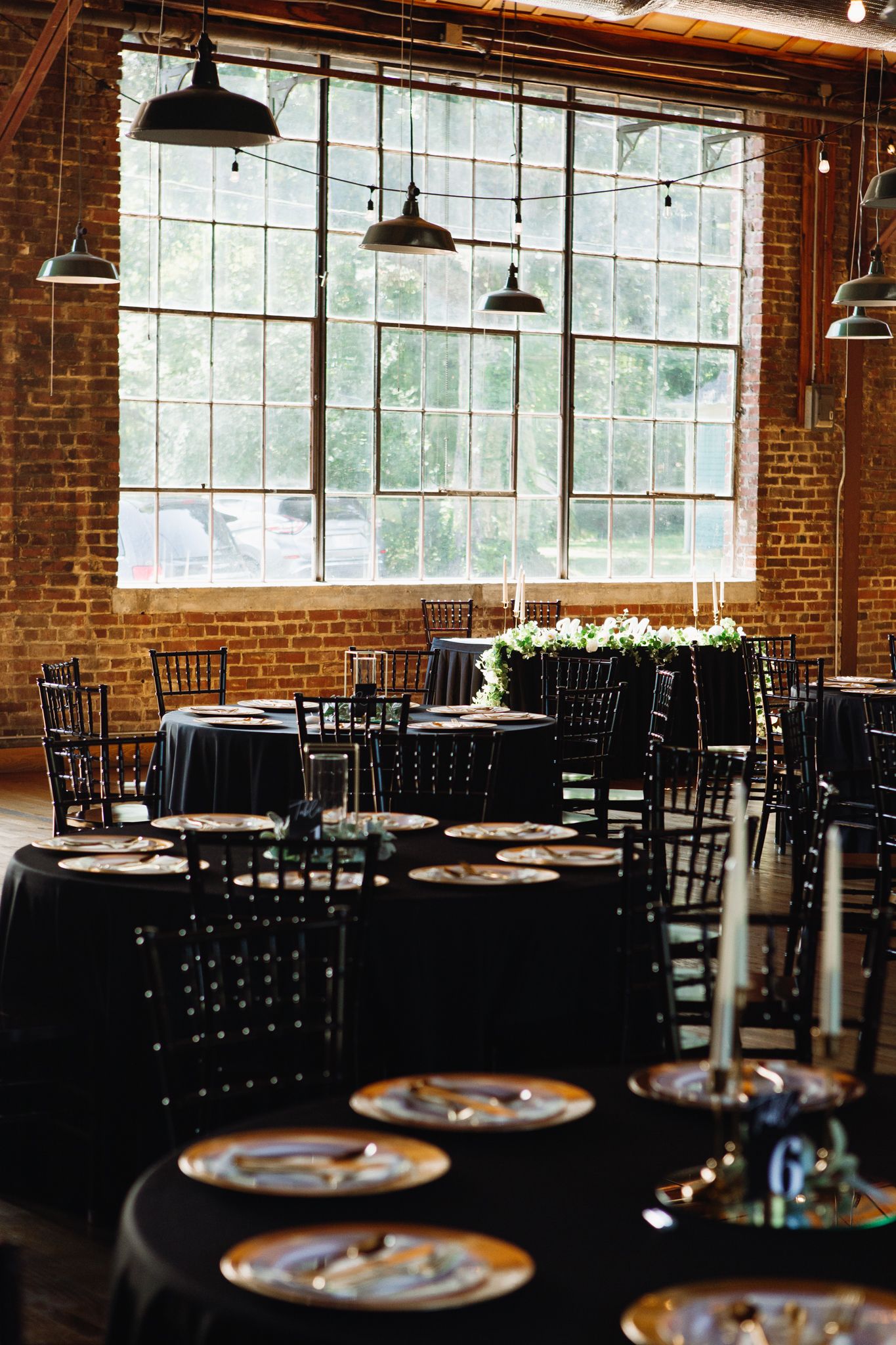A beautifully set long table adorned with flickering candles and lush greenery, creating an inviting atmosphere