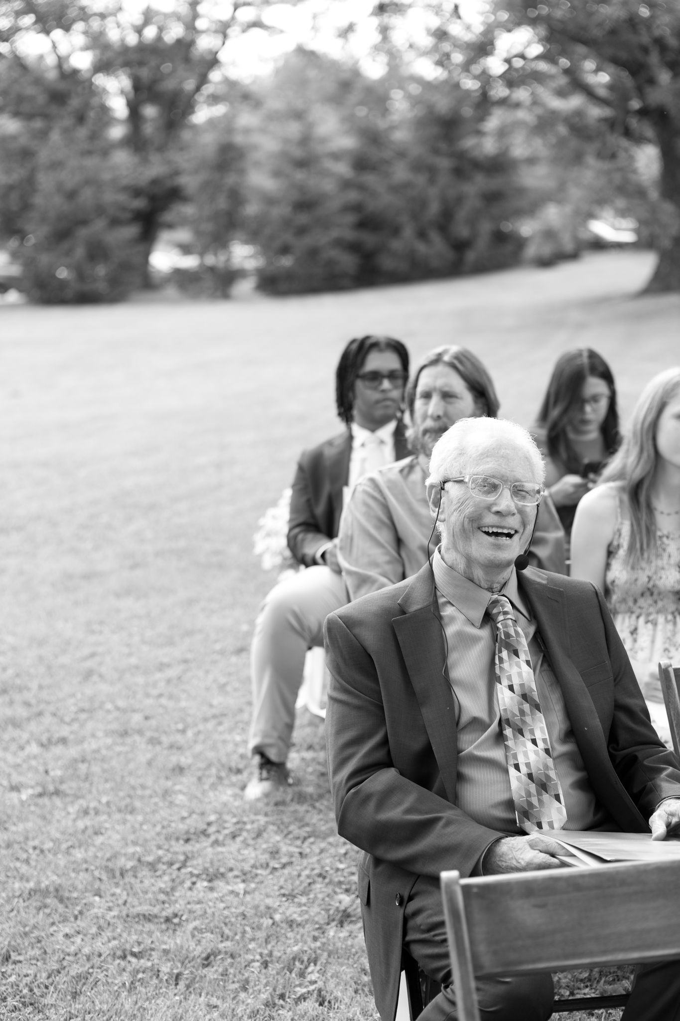 Black and white photo of wedding guests enjoying an outdoor ceremony.