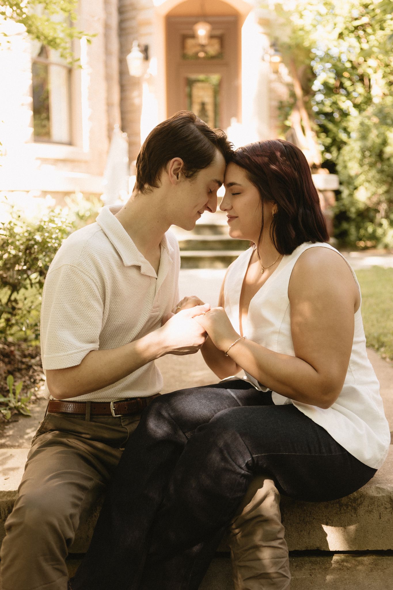 A romantic couple shares an intimate moment while sitting on stone steps in a sepia-toned photograph.