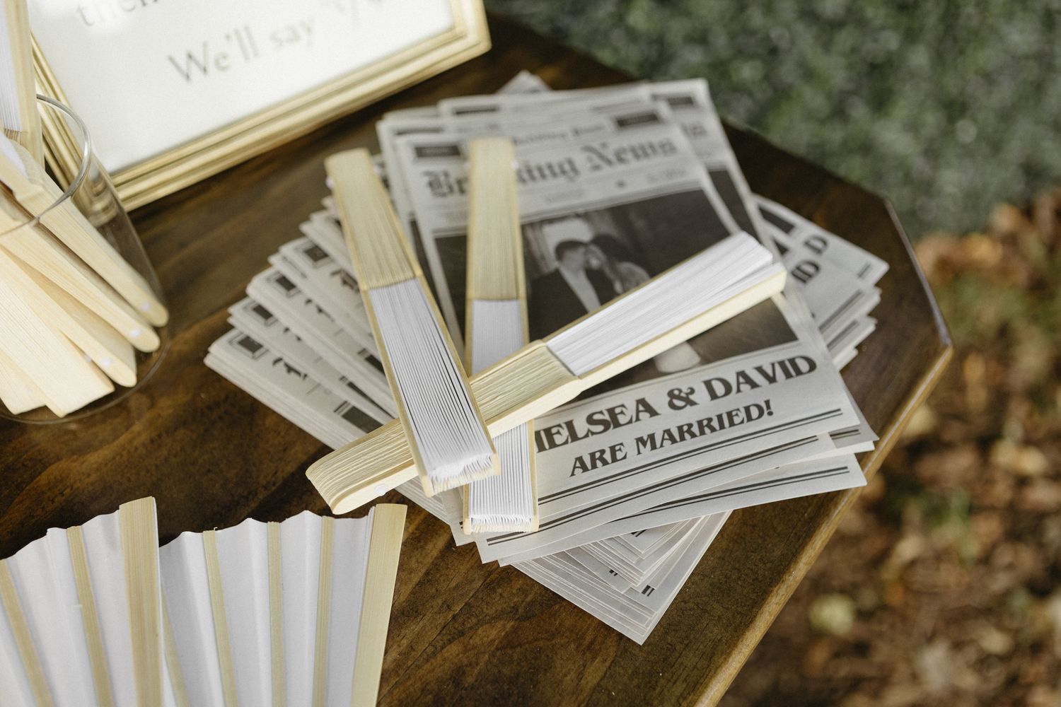 White paper name tags with handwritten names scattered on a dark wooden surface.