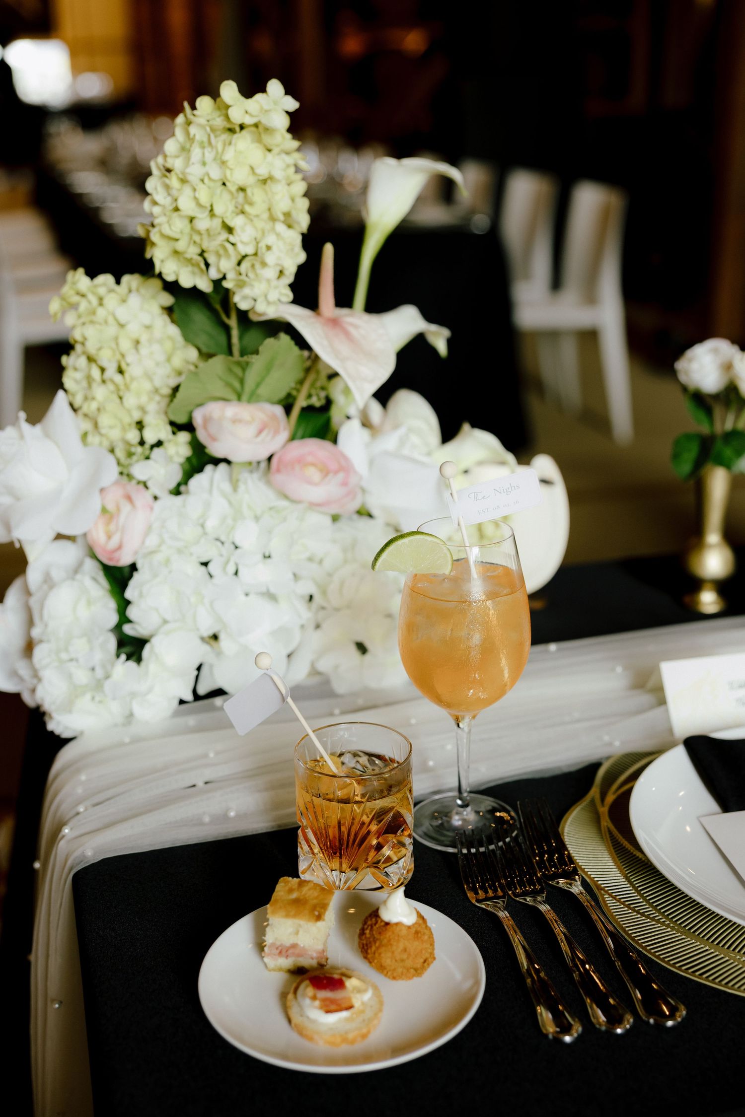 Wedding table setting with hydrangea centerpiece, aperol spritz cocktail, and small appetizer plate.