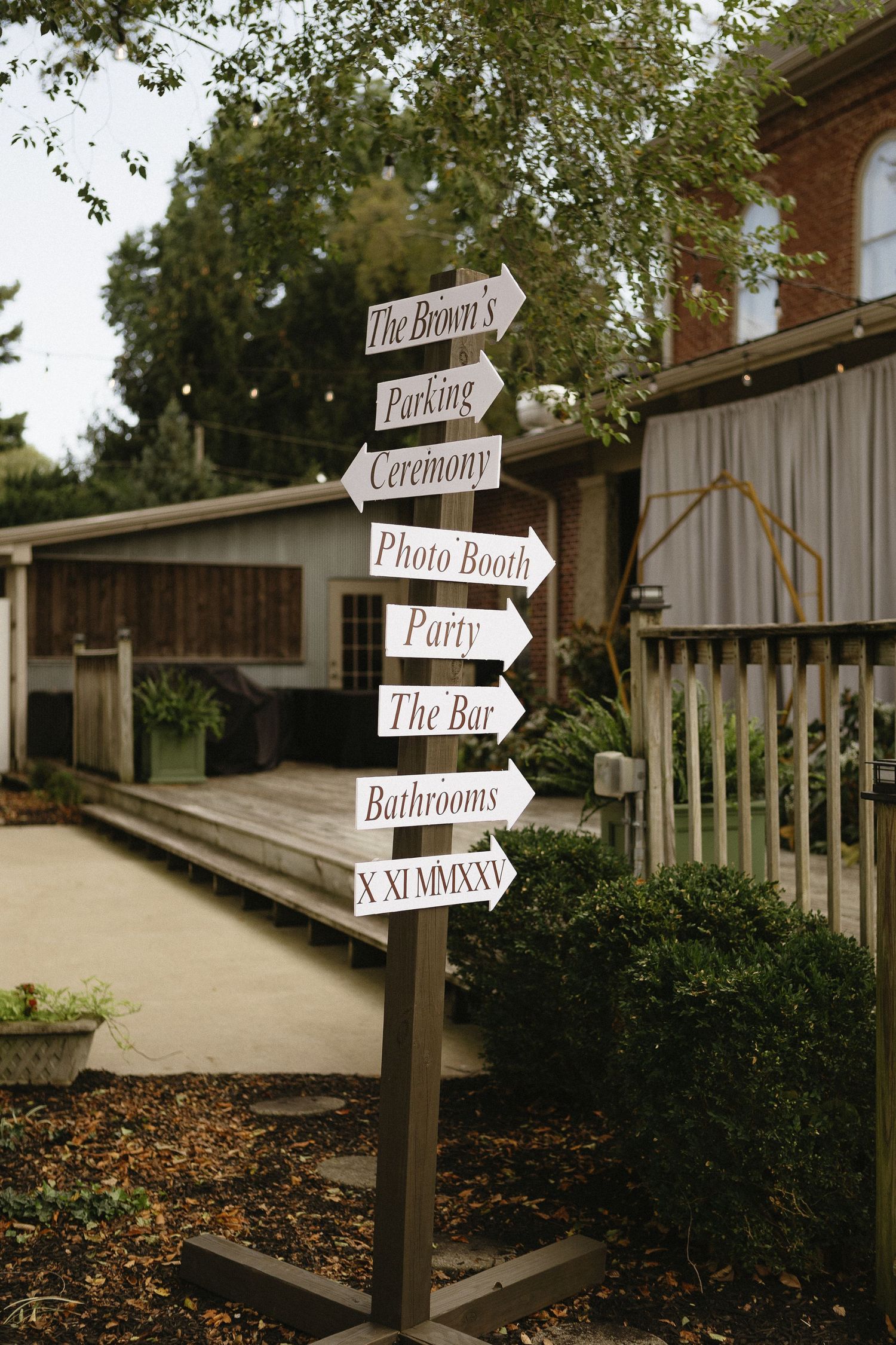 Rustic wooden directional signs pointing to various wedding venue locations and activities.