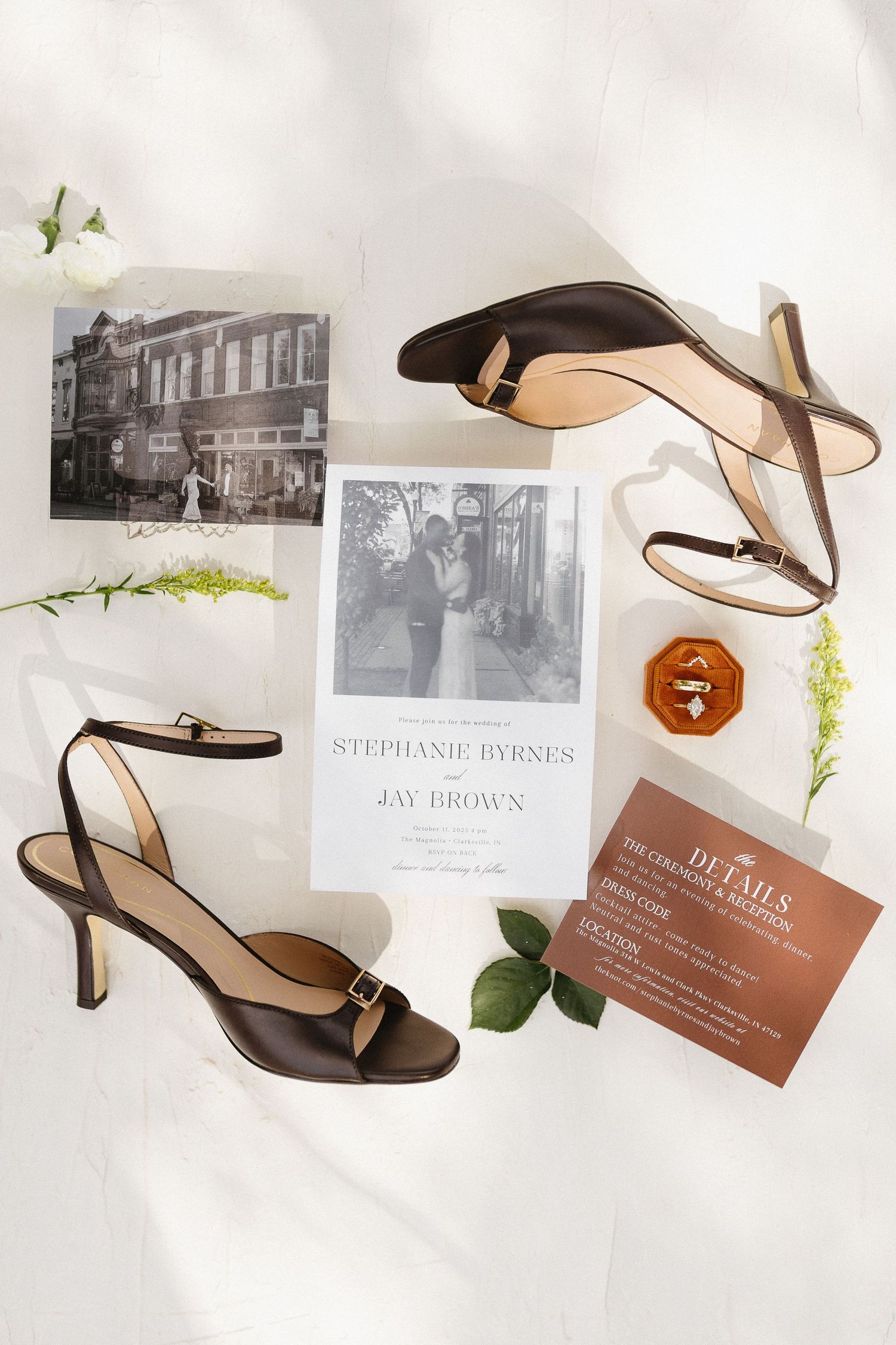 Wedding details including brown leather sandals, invitation cards and vintage photographs arranged on a light background.