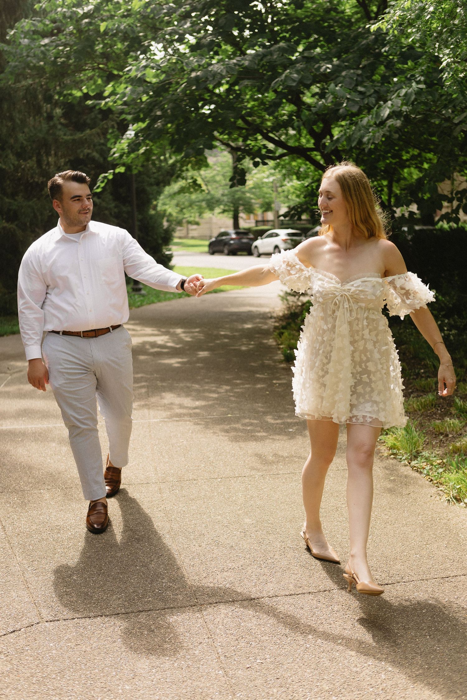 Smiling couple strolling hand in hand on a sunlit garden pathway.