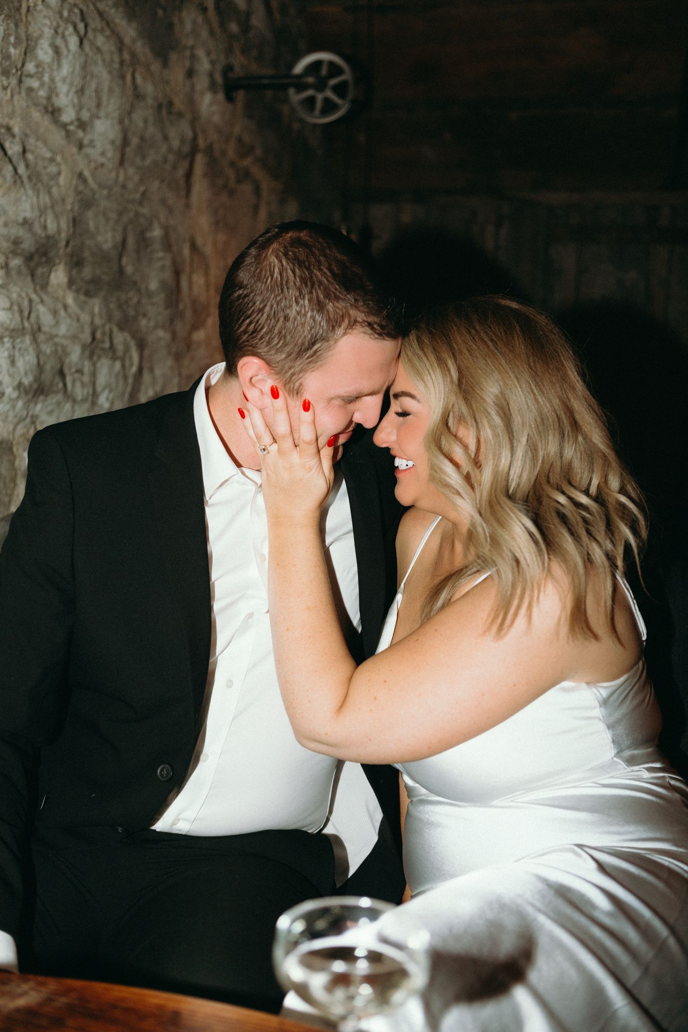 A romantic couple shares a tender moment in an atmospheric dark setting with rustic decor.