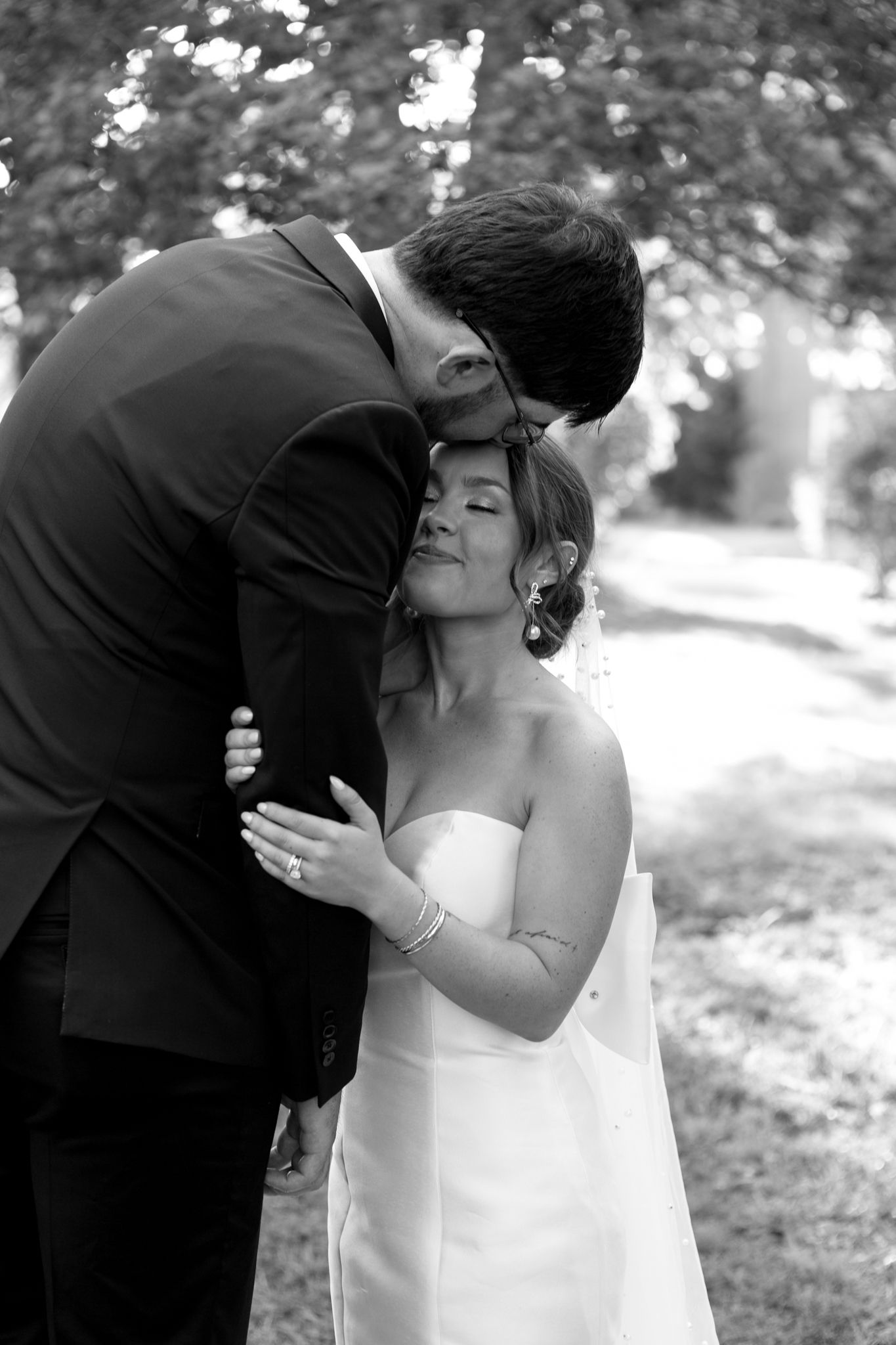 bride and groom share a sweet moment in the backyard, groom gives bride kiss on the forehead