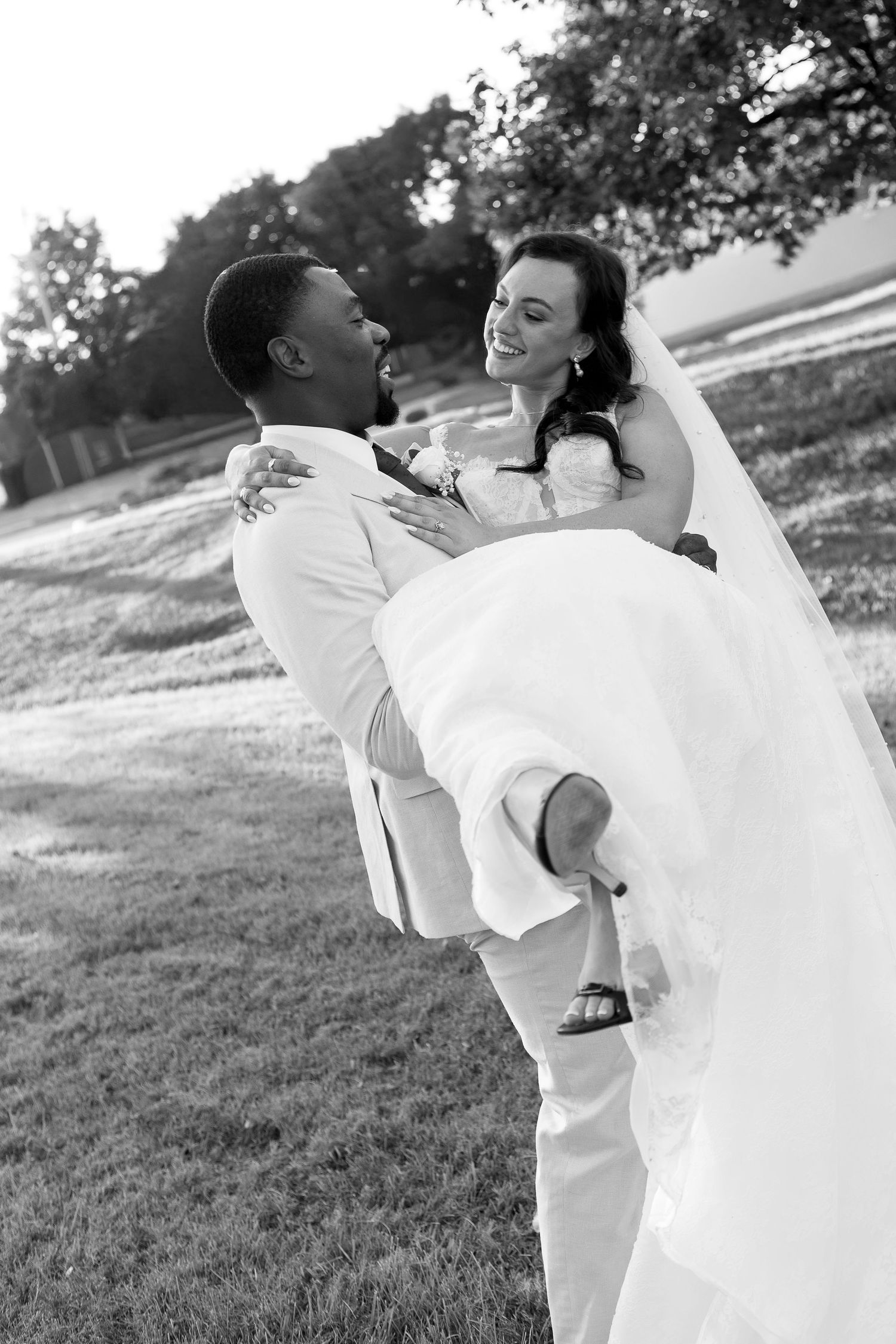Romantic wedding couple dancing and twirling in a sunlit field.