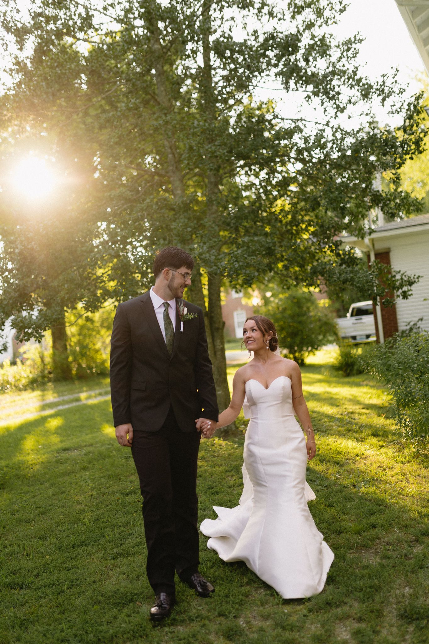 Bride and groom sharing a tender moment in a sunlit grassy field
