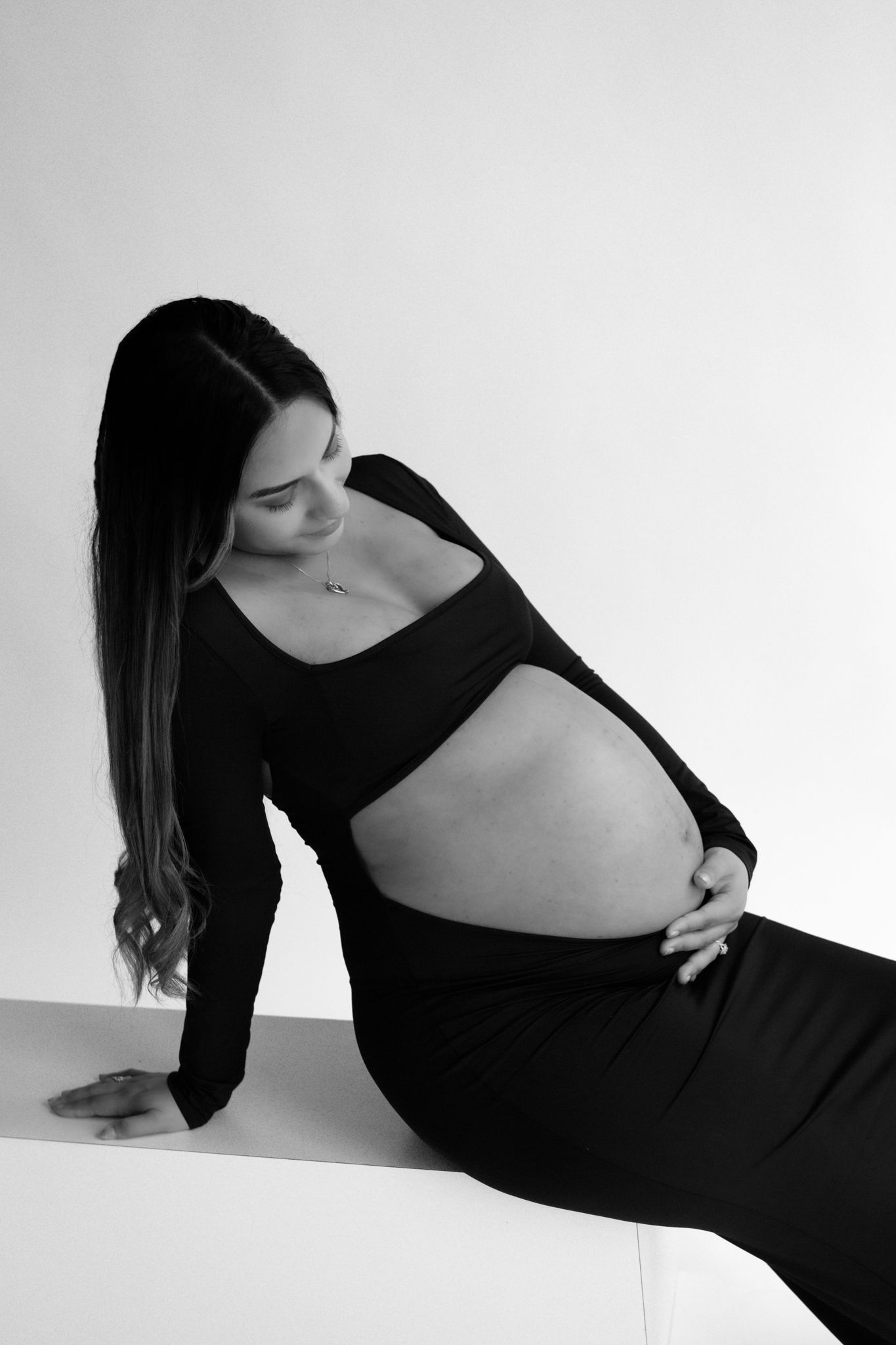 Close-up of a pregnant woman's hands gently cradling her belly, in a serene and intimate indoor maternity photoshoot