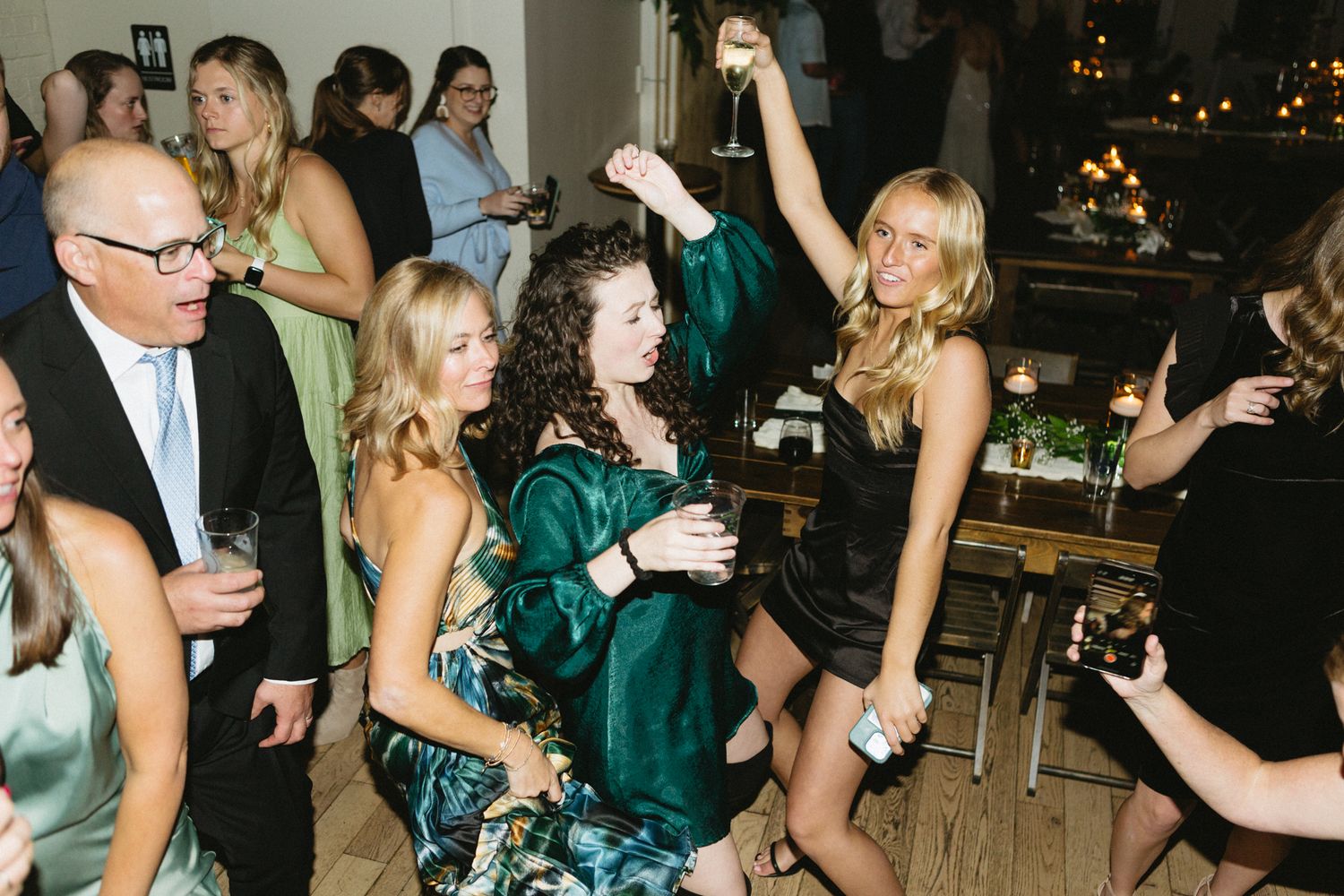 Party guests dancing and celebrating at an elegant indoor venue with ambient lighting.