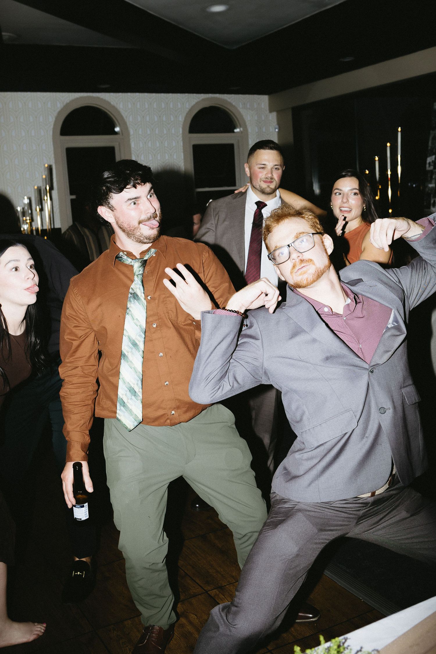 Group of wedding guests performing synchronized dance moves at a reception.
