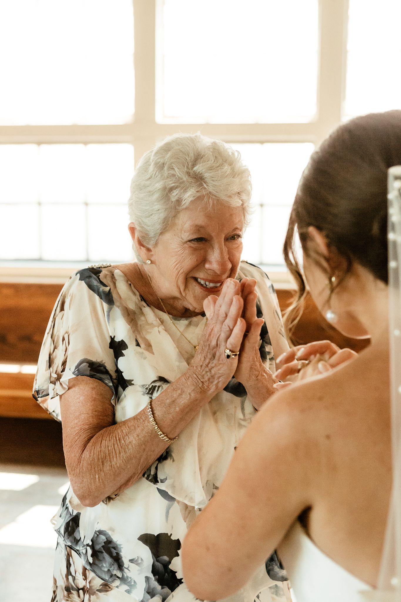 A heartfelt moment as a woman lovingly holds her hand to her grandmother's face, symbolizing care and affection.