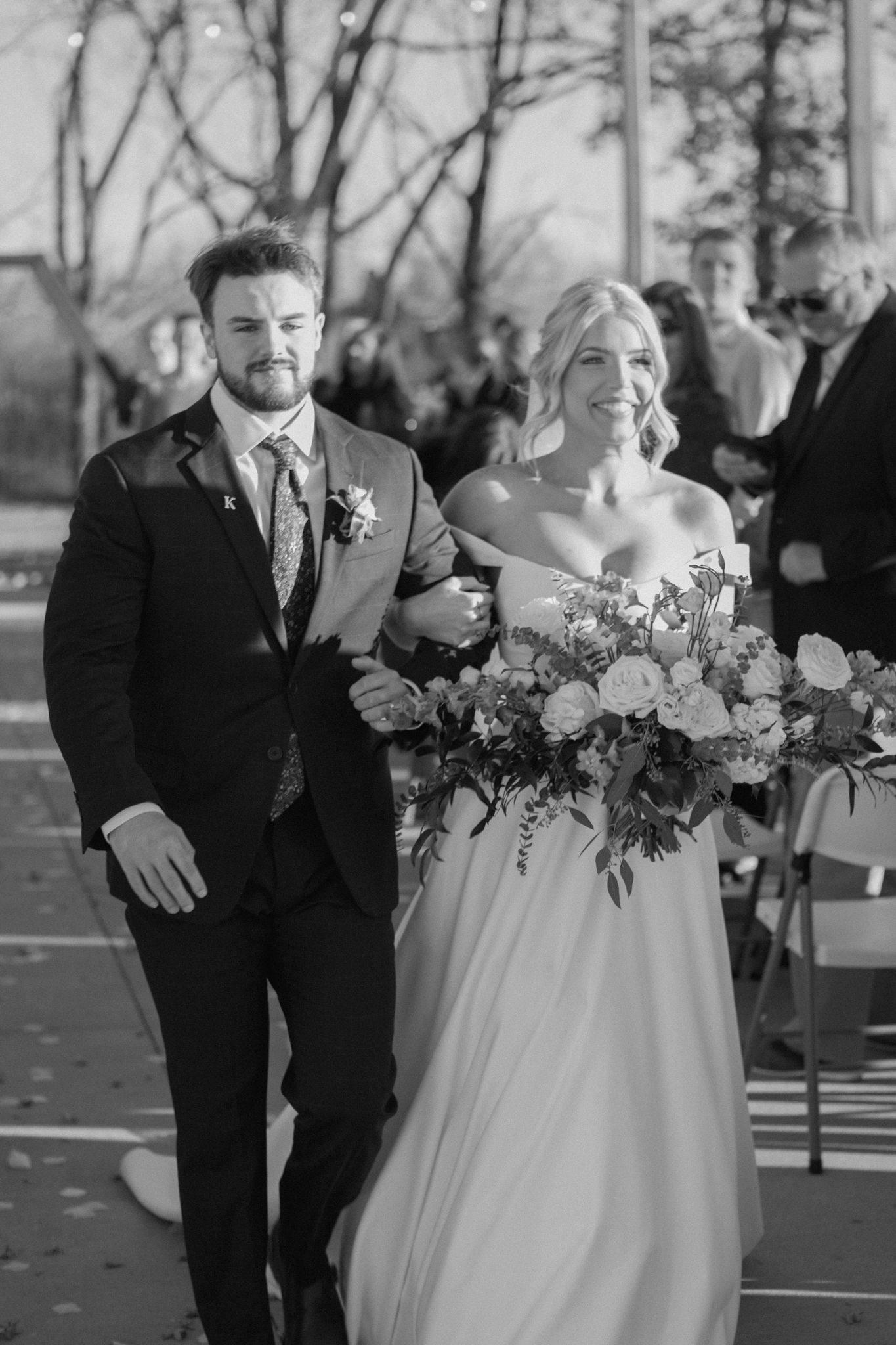 Black and white photo of bride and groom walking down the aisle at Silo Farms, capturing a timeless wedding moment