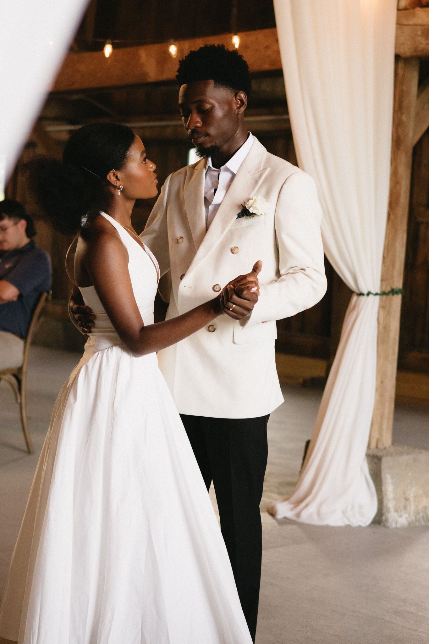 A romantic first dance sequence showing elegant movements in a rustic venue with draped fabric decor.