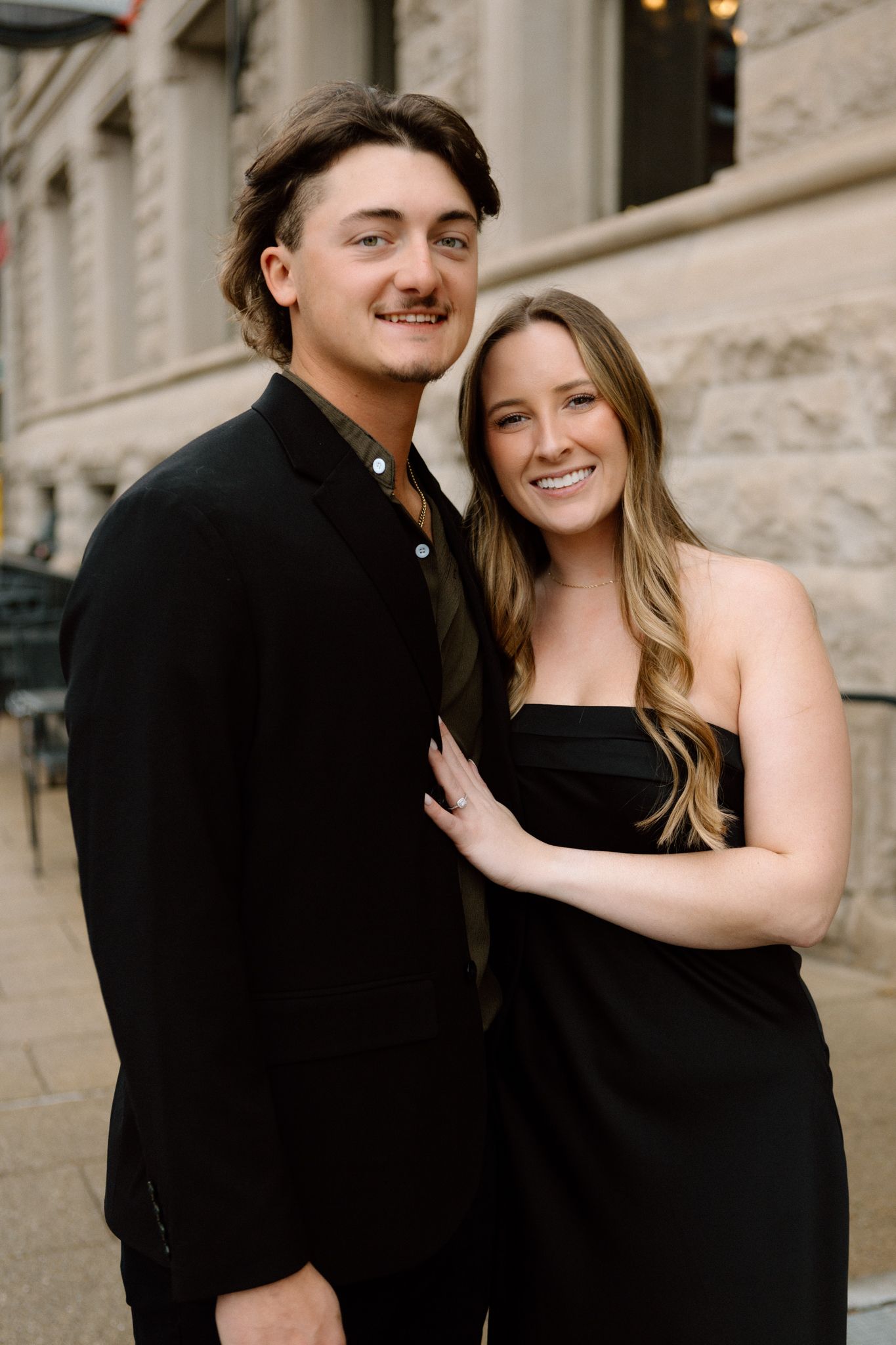 Engaged couple smiling and embracing, captured in downtown Louisville