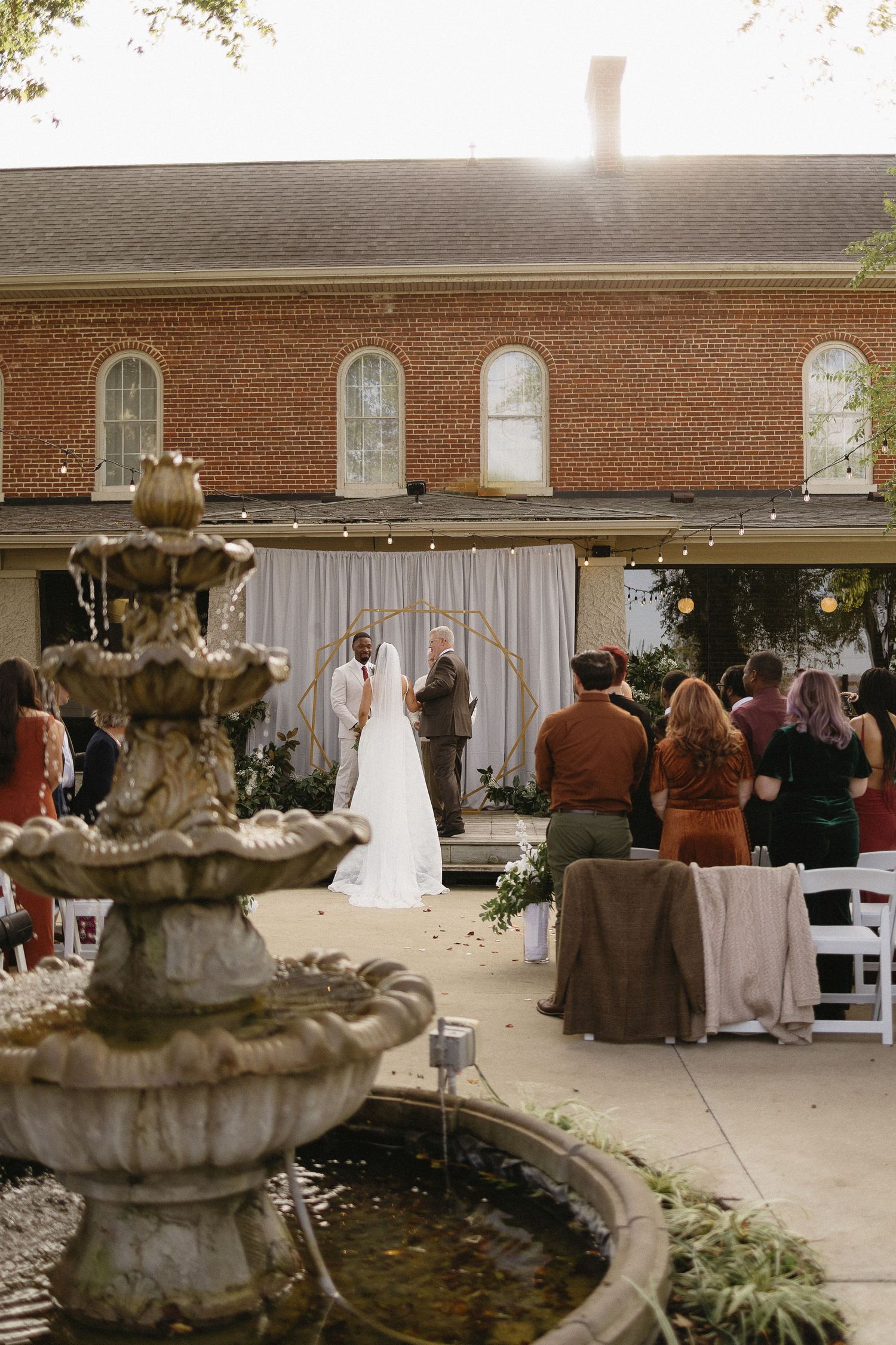 Wedding reception setup in a brick church hall with fountain and elegant white decorations.