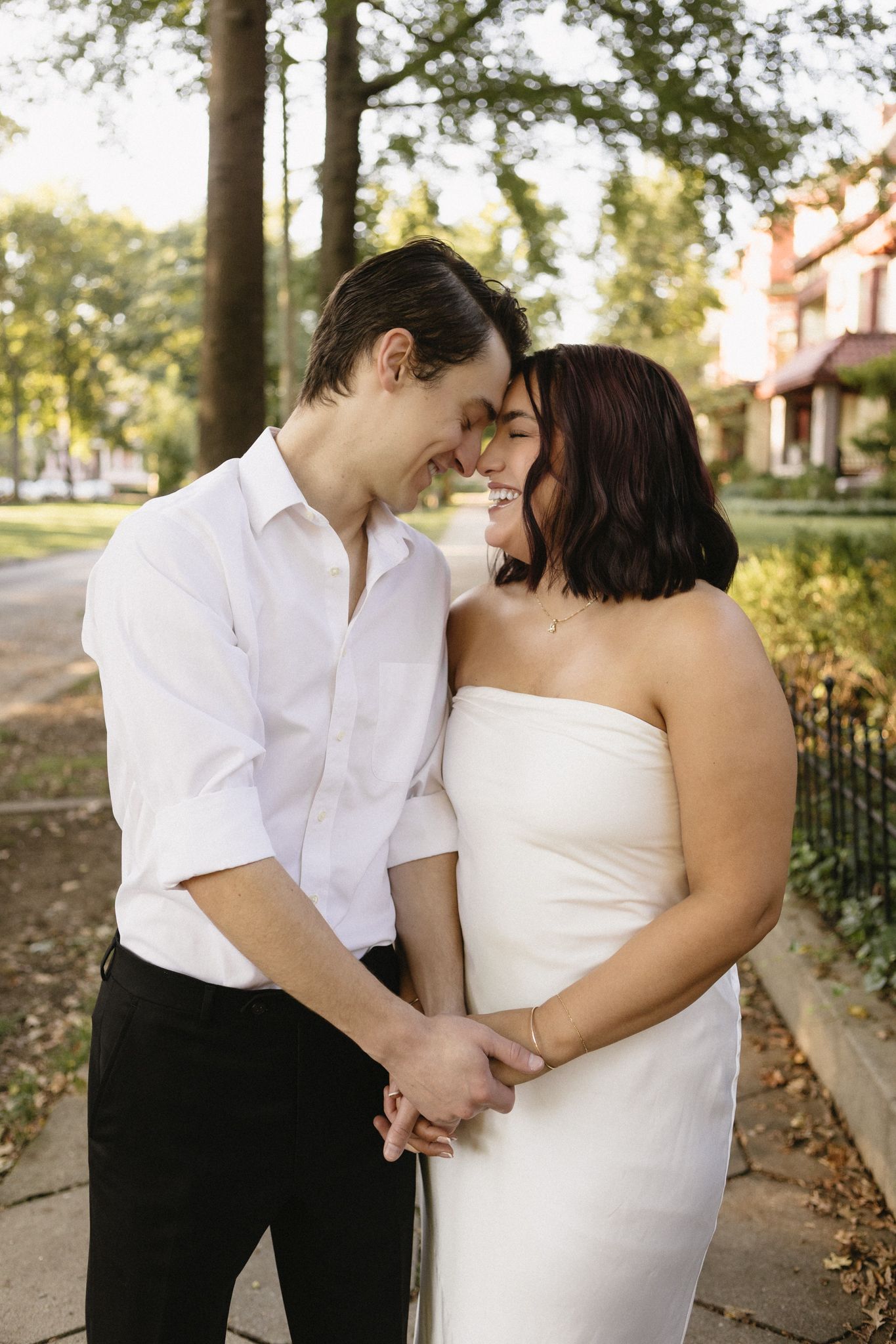 A couple in wedding attire shares intimate moments outdoors during a photo session.