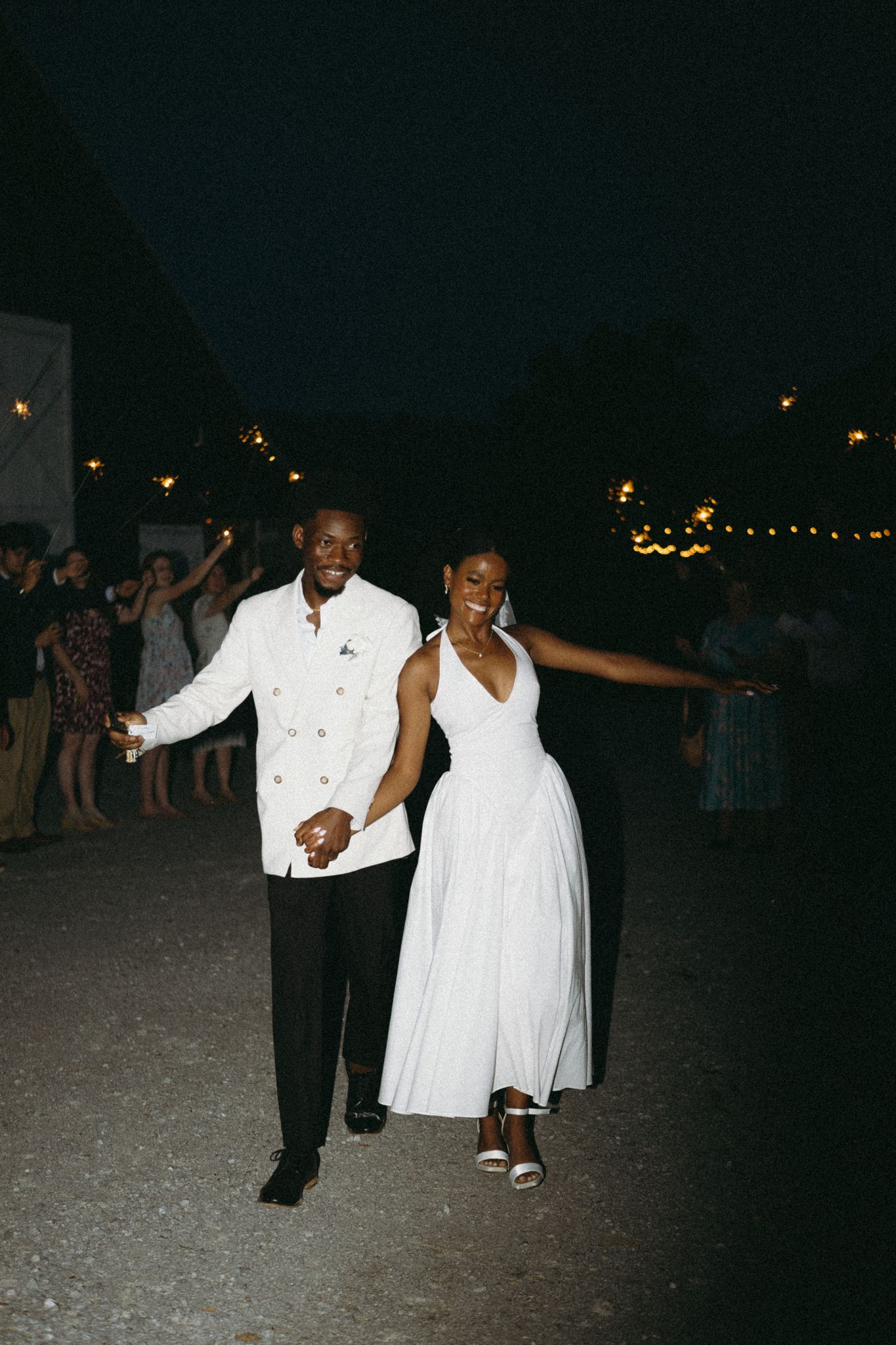 A couple dances together at their nighttime wedding celebration with string lights in background.