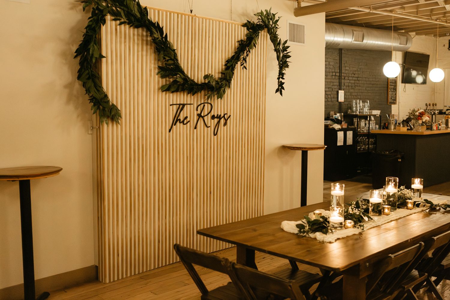 Wedding reception venue with greenery arch and wooden decor featuring 'The Ring' signage.
