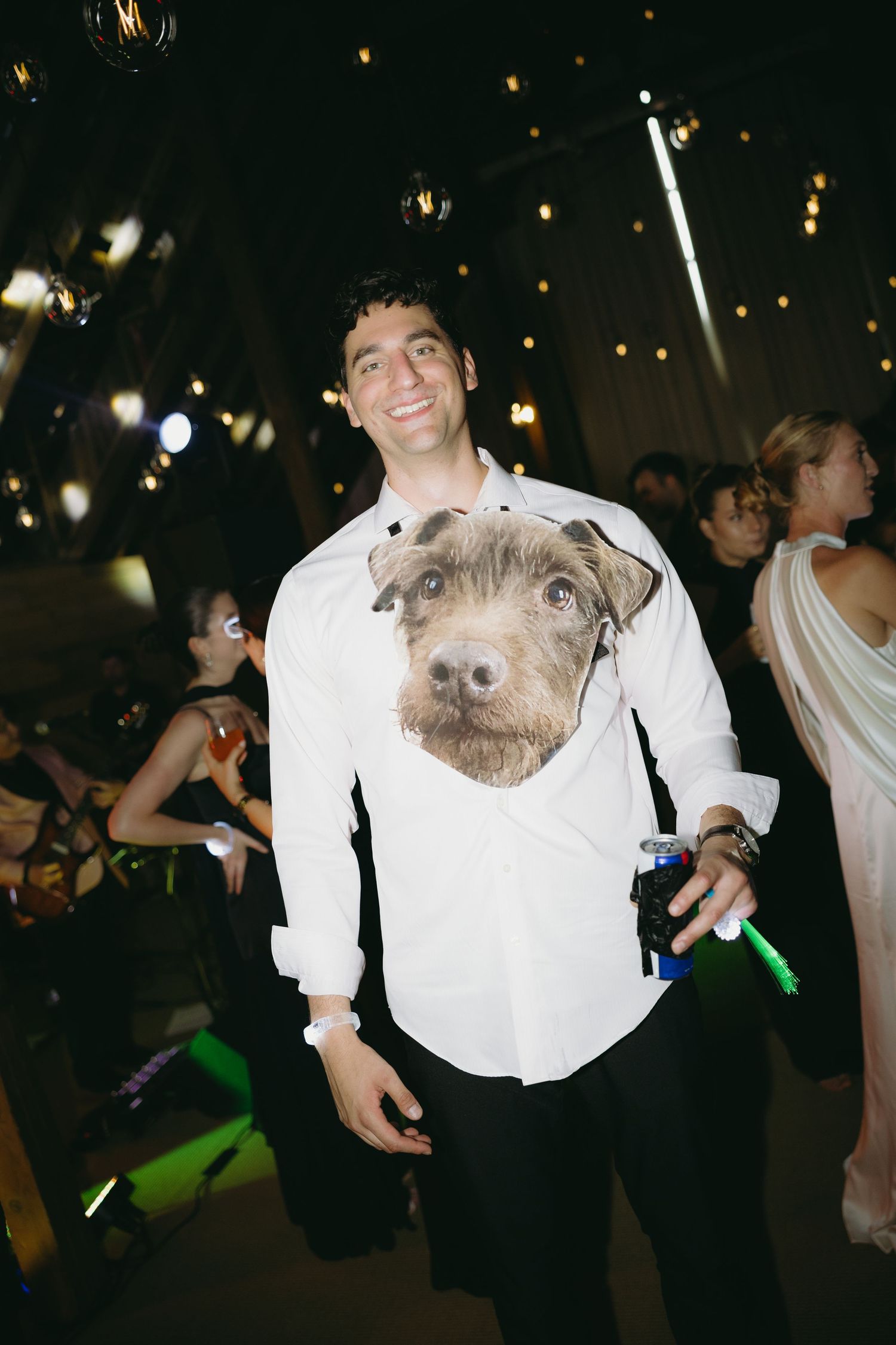 Smiling wedding guest wearing fun dog-print shirt at lively evening wedding reception party.