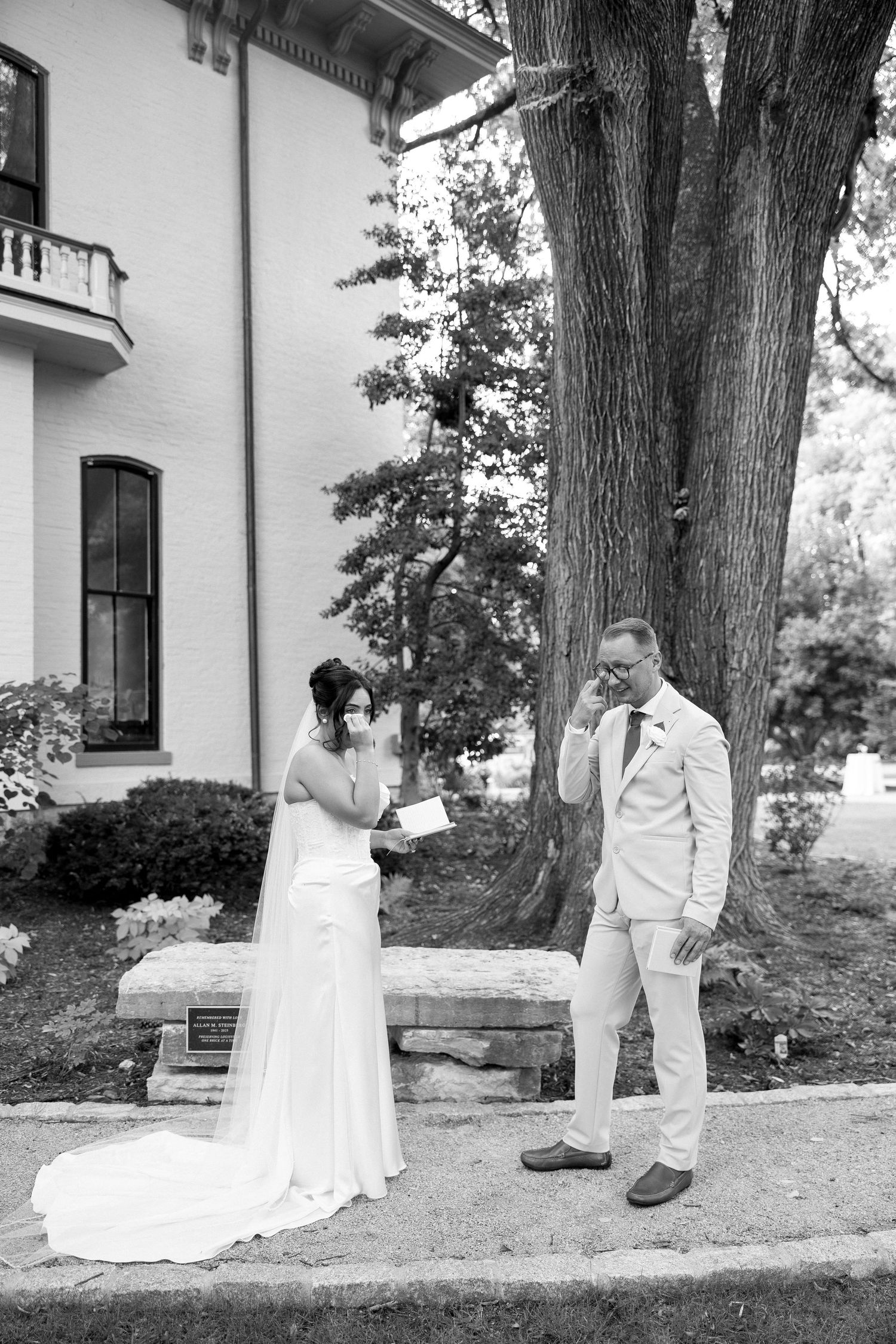 Black and white photo of emotional bride and groom exchanging private vows outside historic mansion.