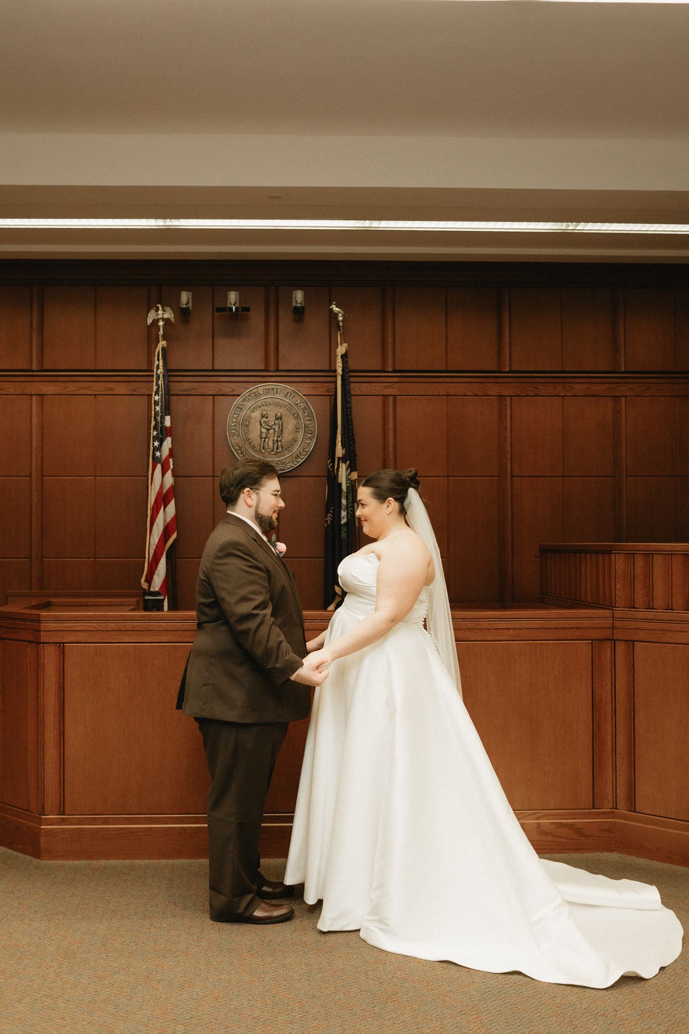 A wedding ceremony sequence showing a couple in formal attire exchanging vows in a wood-paneled courtroom setting.