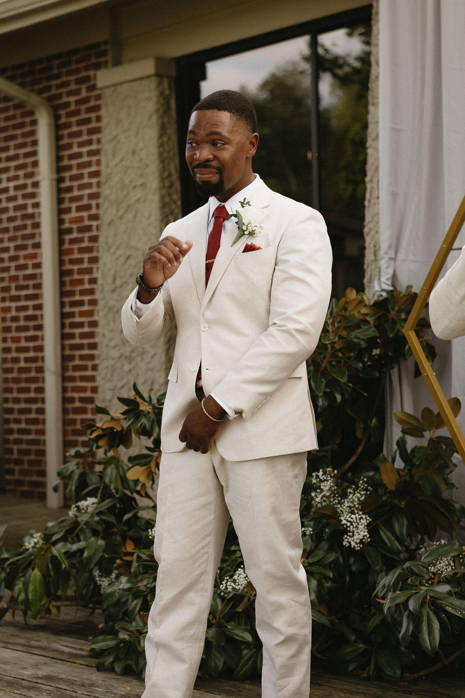 Wedding party members in cream-colored suits posing outside a brick building.