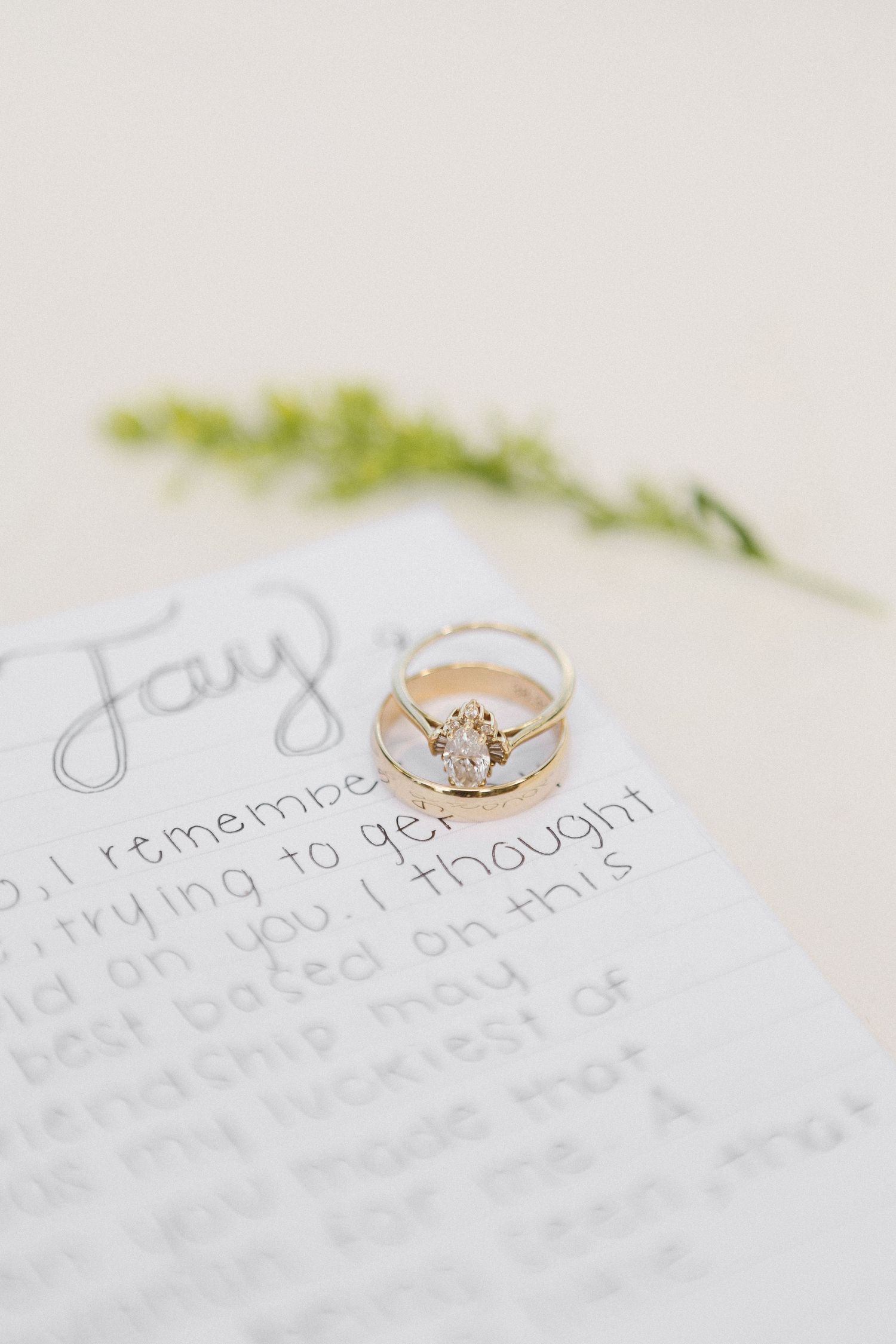 Close-up view of delicate engagement rings with diamond solitaires on handwritten text background.