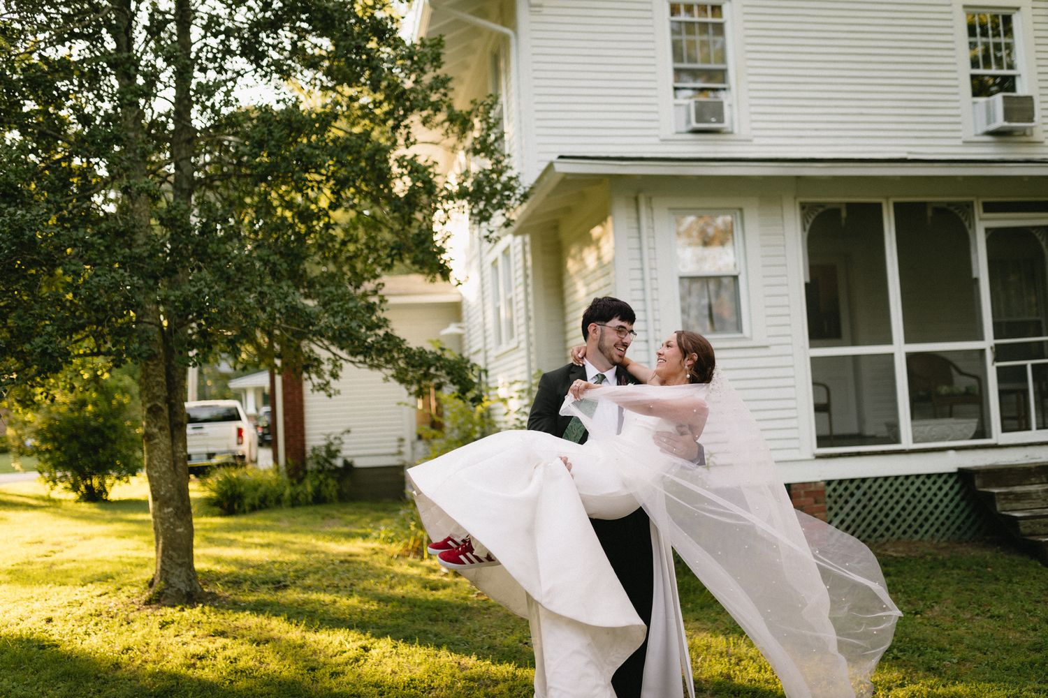 Bride and groom sharing a tender moment in a sunlit grassy field