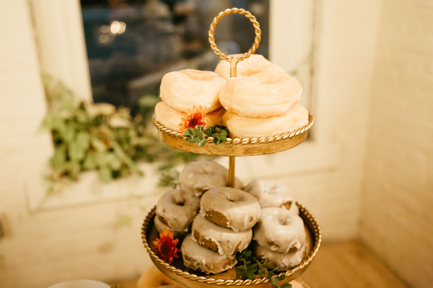 Two-tiered dessert stand with macarons and other sweets displayed at an elegant wedding reception.