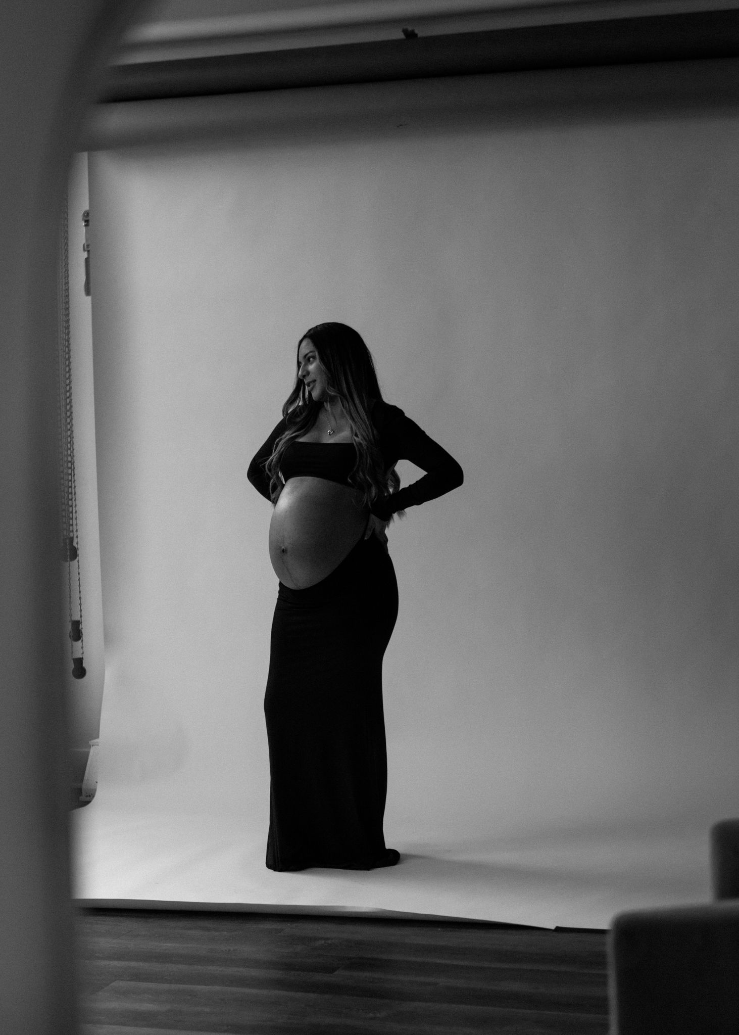 Close-up of a pregnant woman's hands gently cradling her belly, in a serene and intimate indoor maternity photoshoot