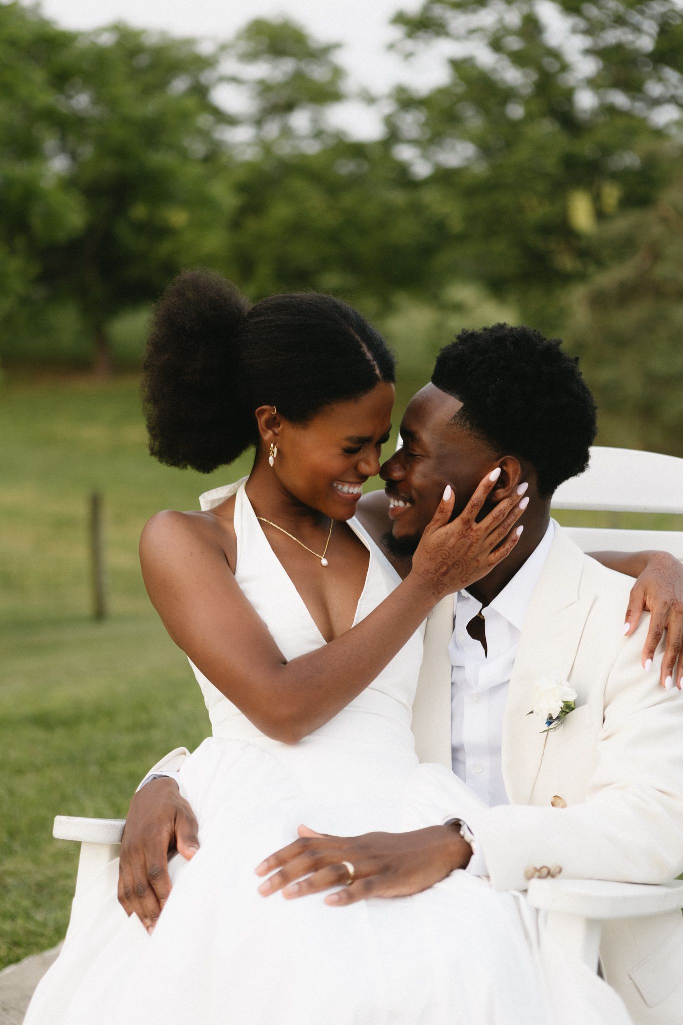 Intimate wedding couple shares tender romantic moments while dressed in crisp white formal attire outdoors.