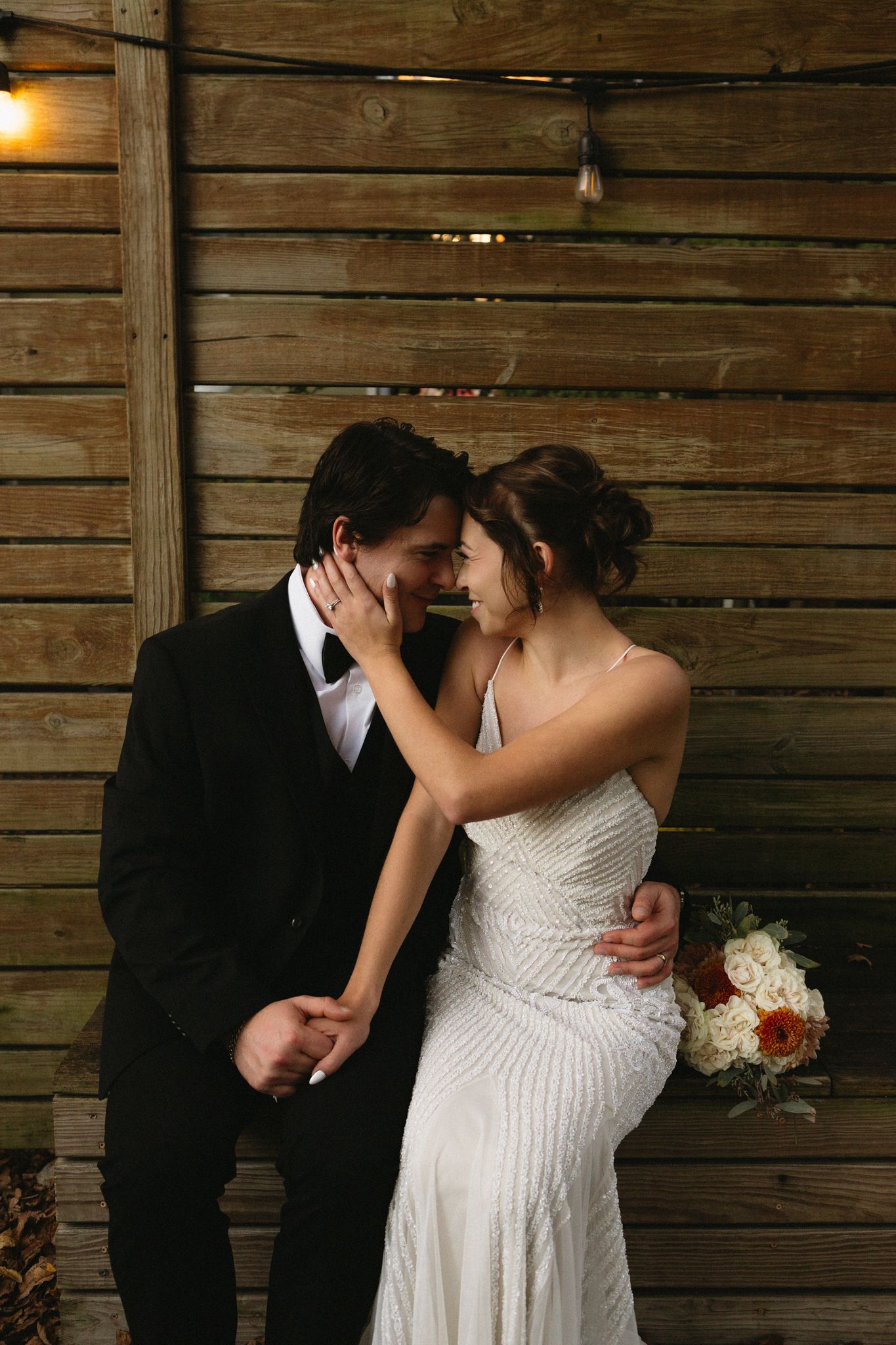 An intimate wedding moment against rustic wooden walls as the couple embraces.