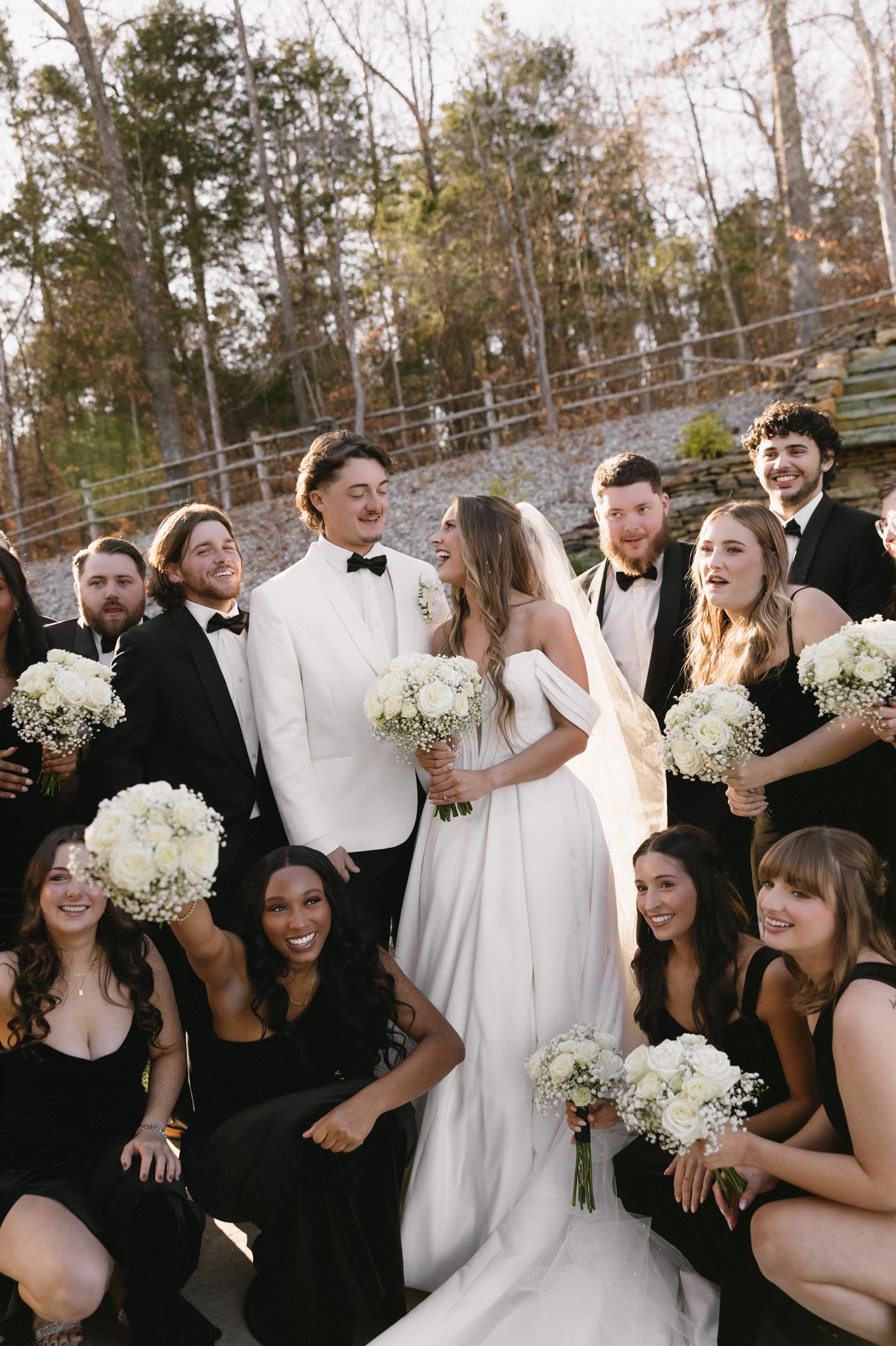 Candid wedding party photo with bridesmaids in black dresses and groomsmen in formal wear.