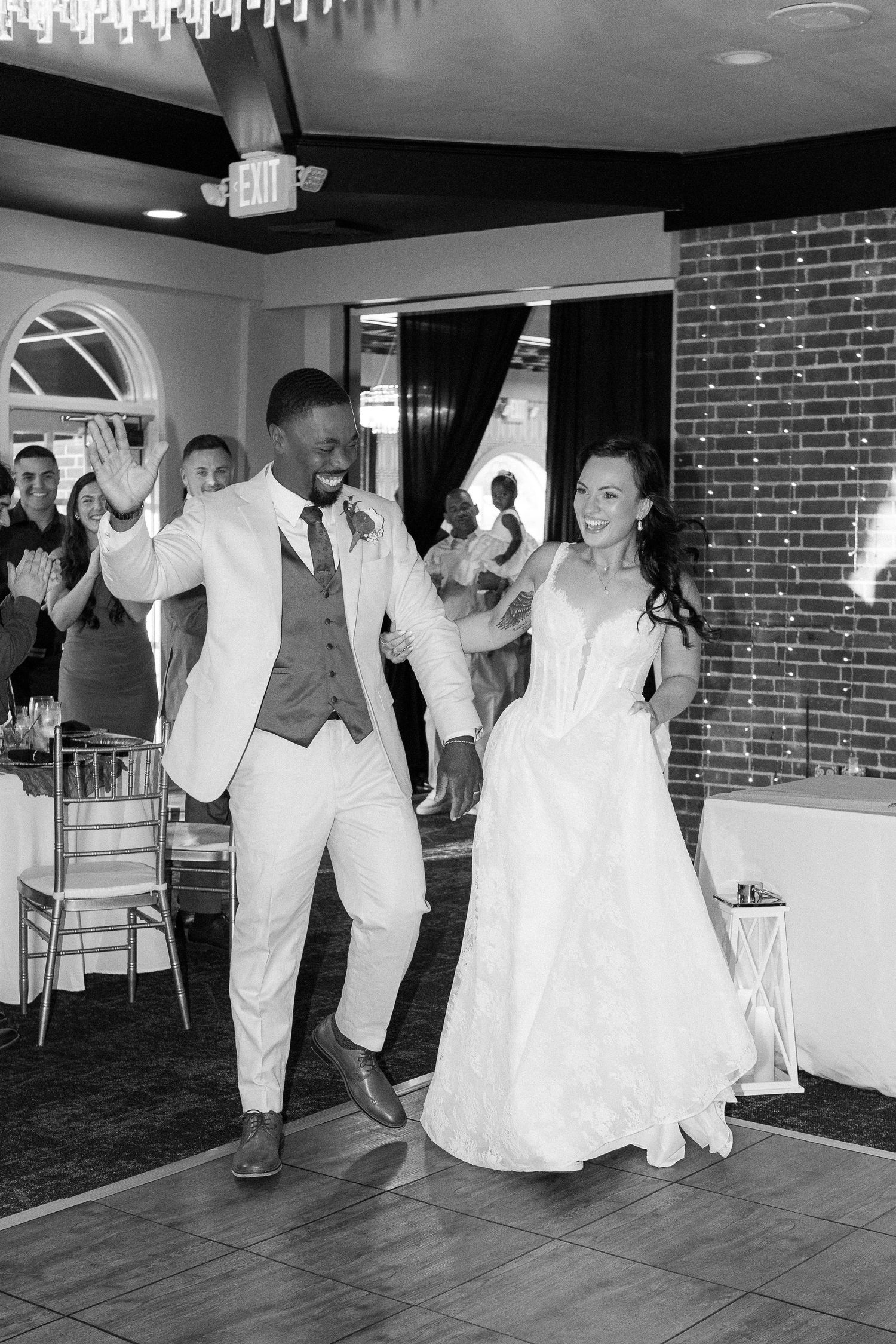 Wedding party dancing and celebrating in formal attire at indoor reception venue.