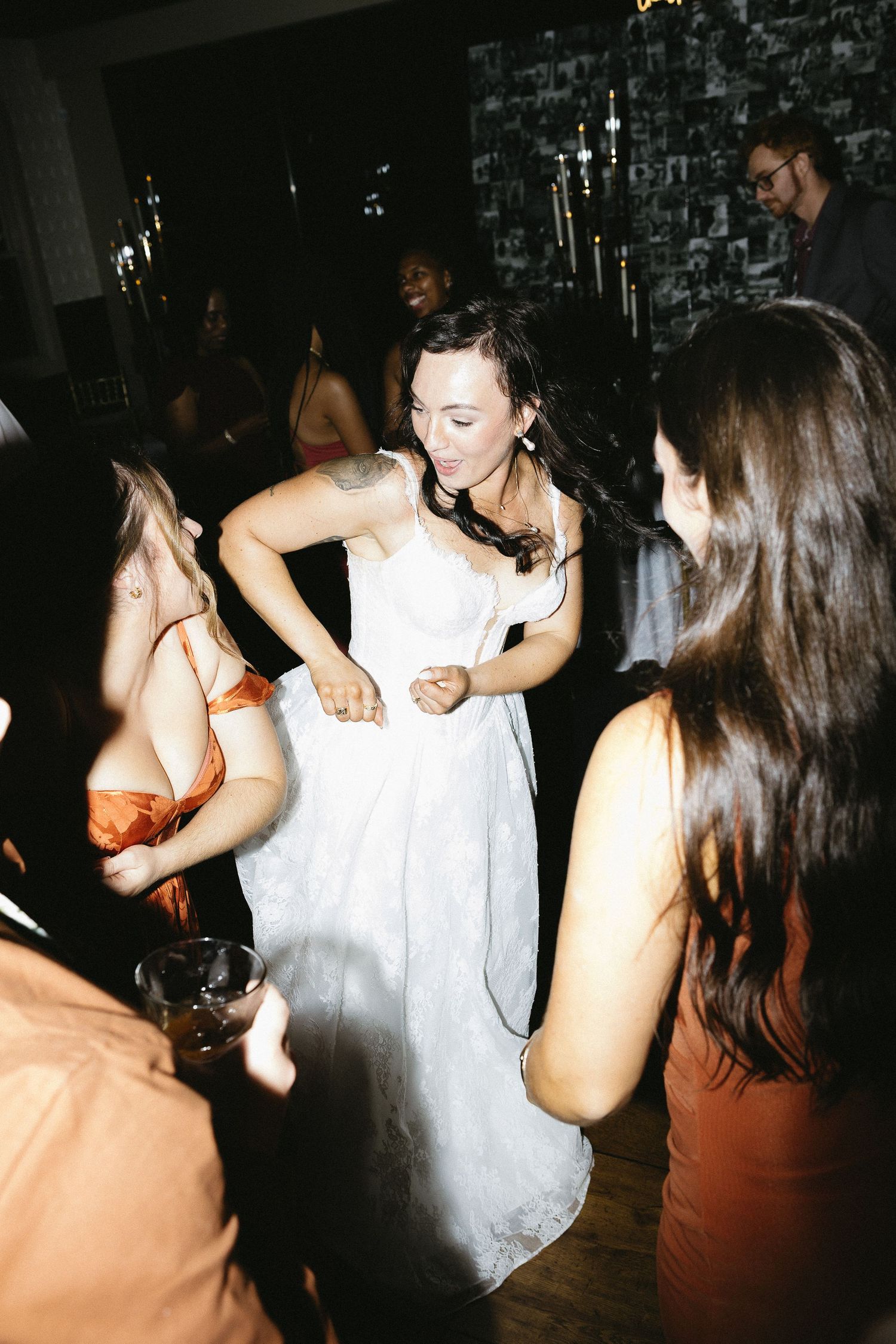Wedding reception dance party with guests dancing and celebrating in a dark venue with flash photography.