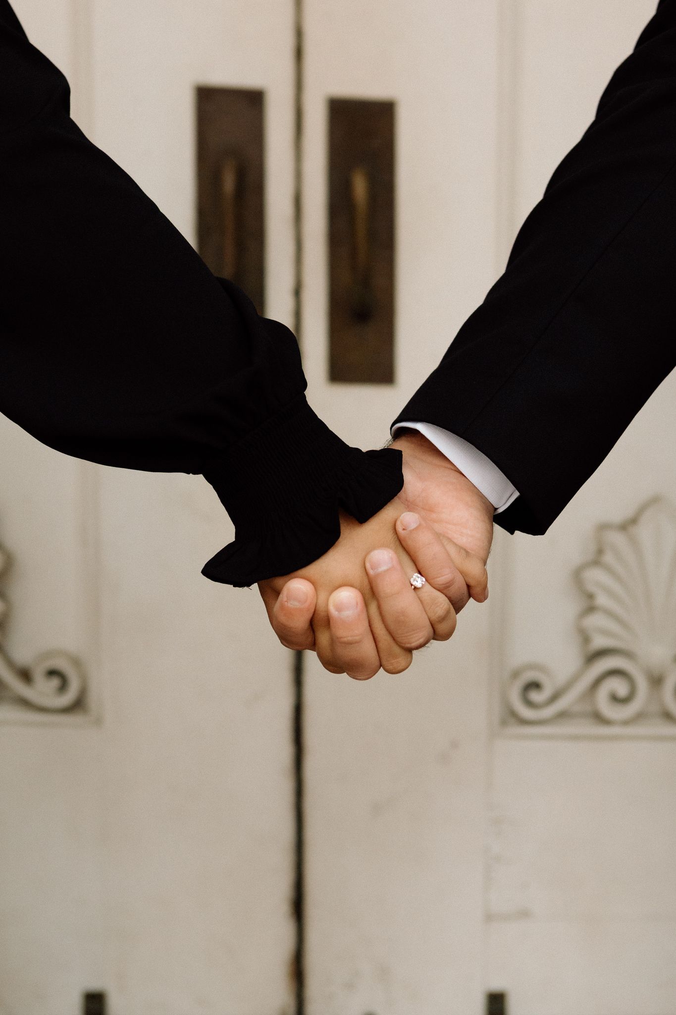Elegant engaged couple smiling and embracing in downtown Louisville, with the woman showing her engagement ring