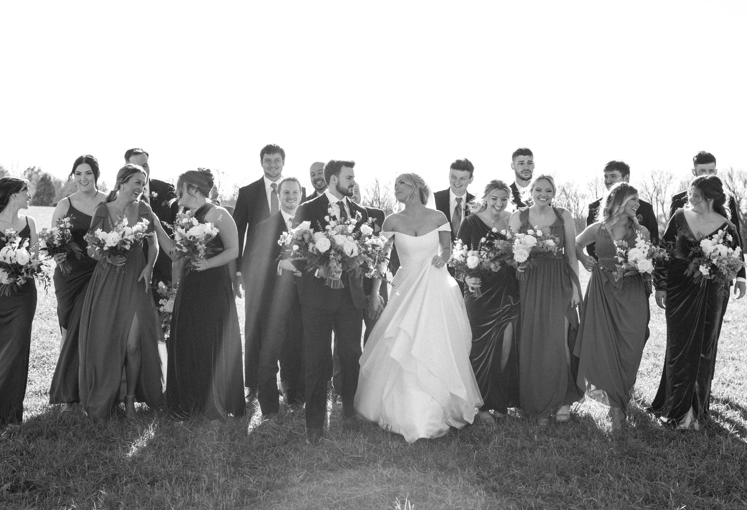 Bride, groom, and entire bridal party posing together for a joyful wedding photo